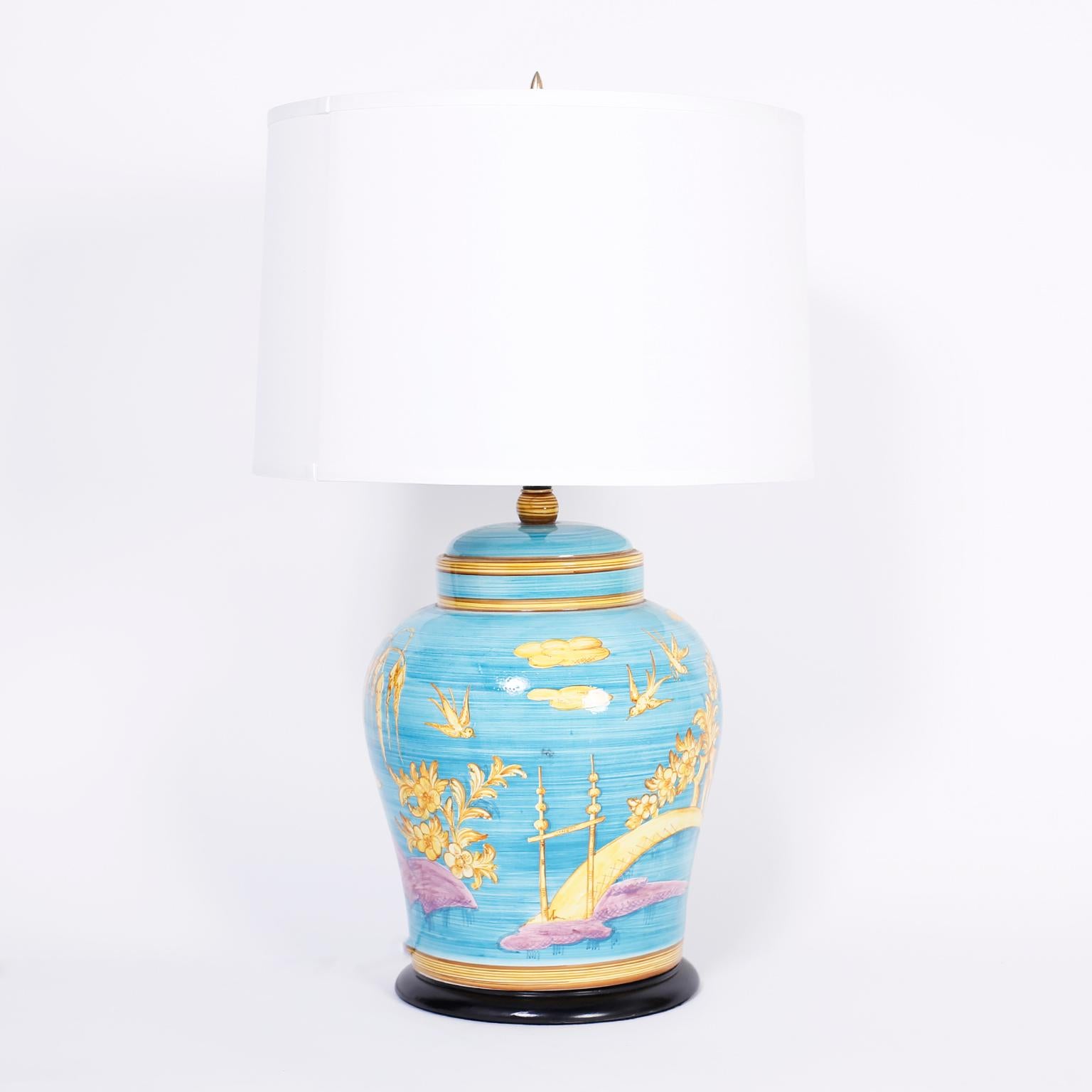 Pair of midcentury ceramic table lamps with a classic ginger jar form, decorated all around with bold chinoiserie designs in gold against an alluring turquoise background and set on black lacquered wood bases.