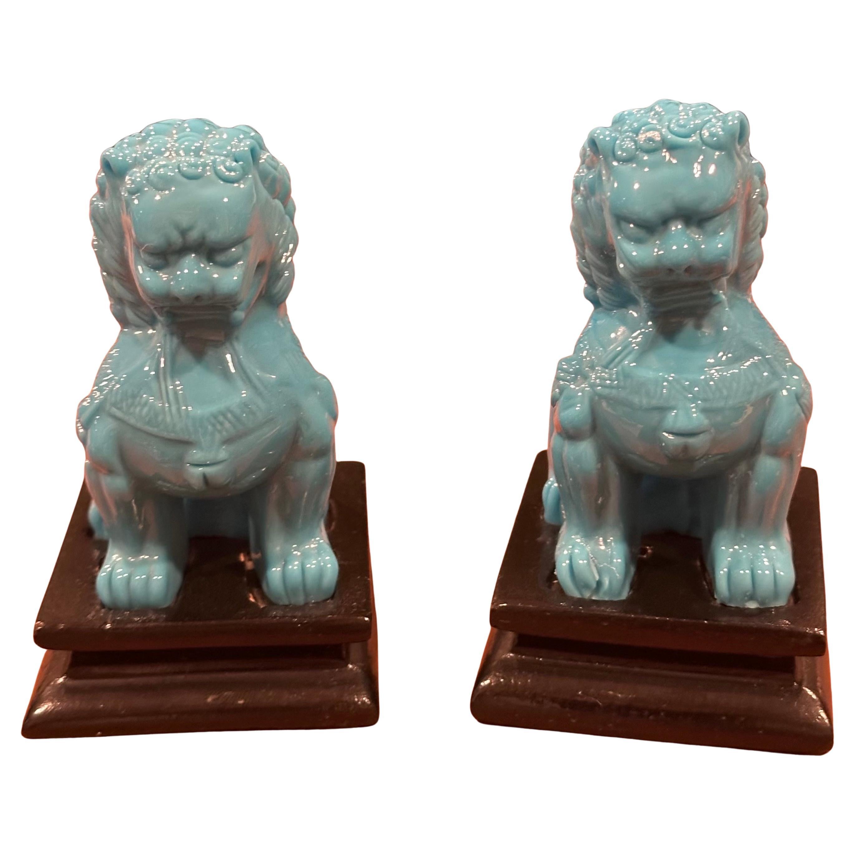 Belle paire de sculptures de chien de foo en verre bleu opaque turquoise du milieu du siècle sur des bases en bois, vers les années 1970. Ces gardiens symboliques présentent une belle teinte turquoise et sont en très bon état vintage à l'exception