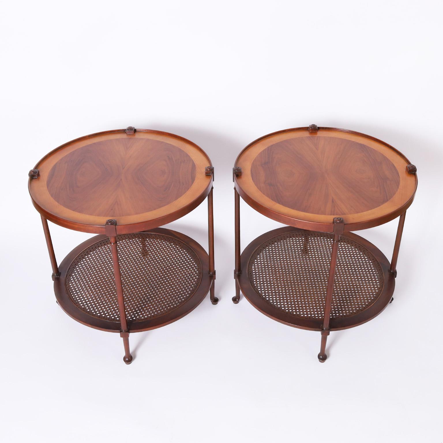 Chic pair of vintage stands having round tops featuring lush grained walnut in a bookmatch technique framed in mahogany as are the supports and caned lower tier with Queen Anne style feet. Signed Baker on a silver label.