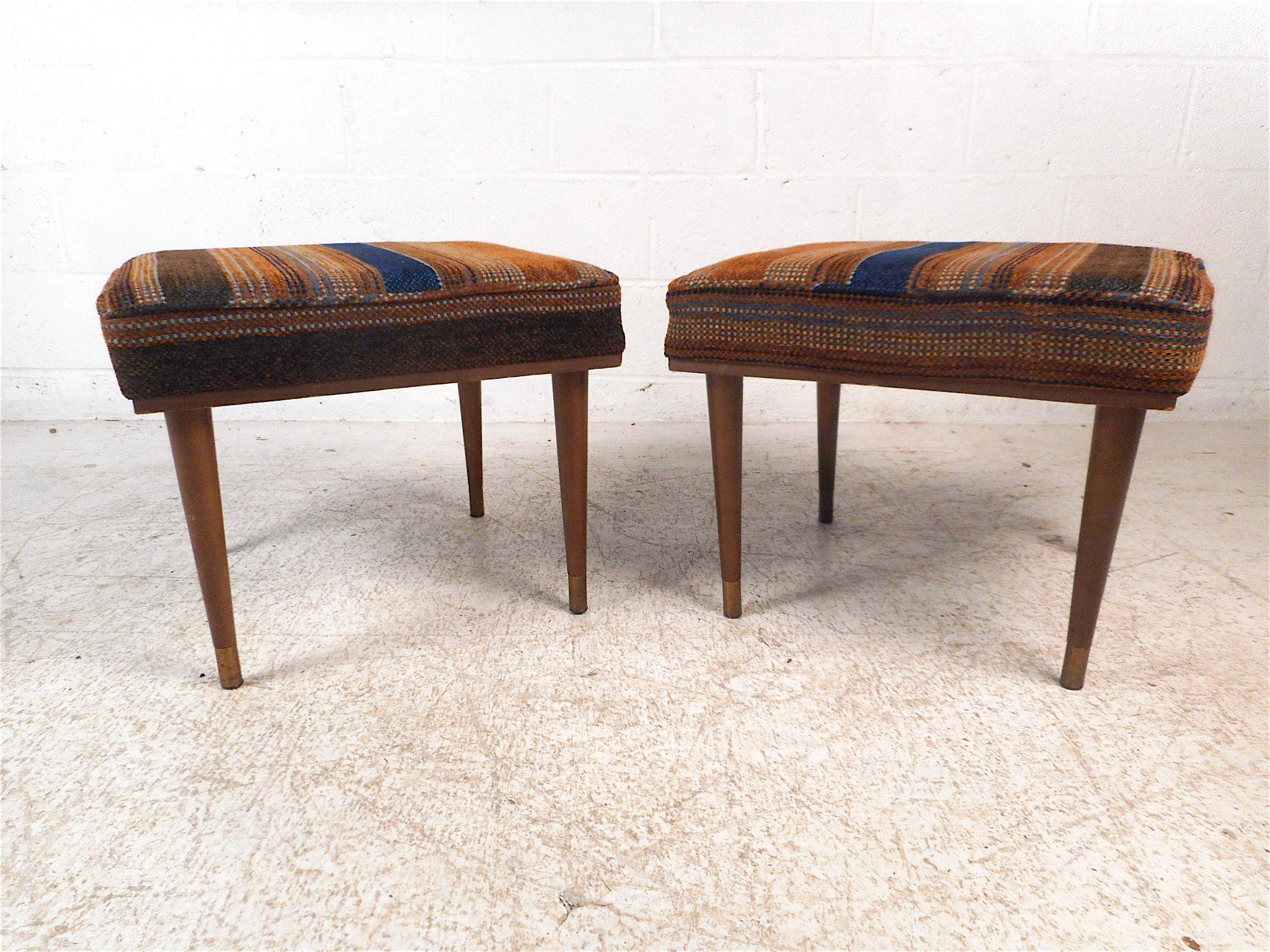 Stylish pair of midcentury ottomans. Tapered wooden legs with brass accents at the base, cushions covered in a vintage striped upholstery. Great addition to any modern interior. Please confirm item location with dealer (NJ or NY).