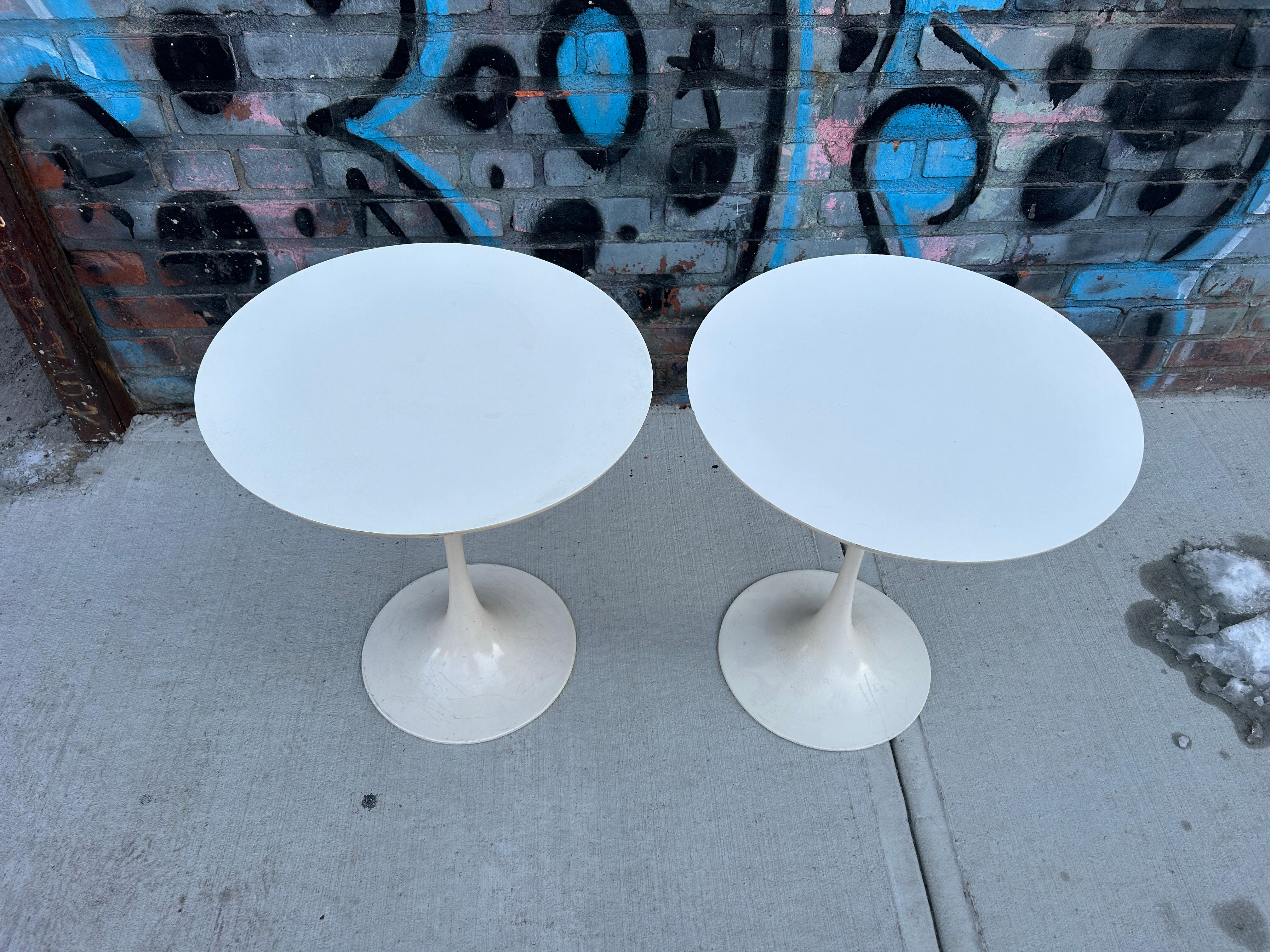 Pair mid Century vintage white Laminate Tulip side tables. In the style of Knoll Tulip round end tables in white Laminate with off white painted metal base. Good vintage condition. Great set of Vintage mid century end tables by Burke Inc. No labels.