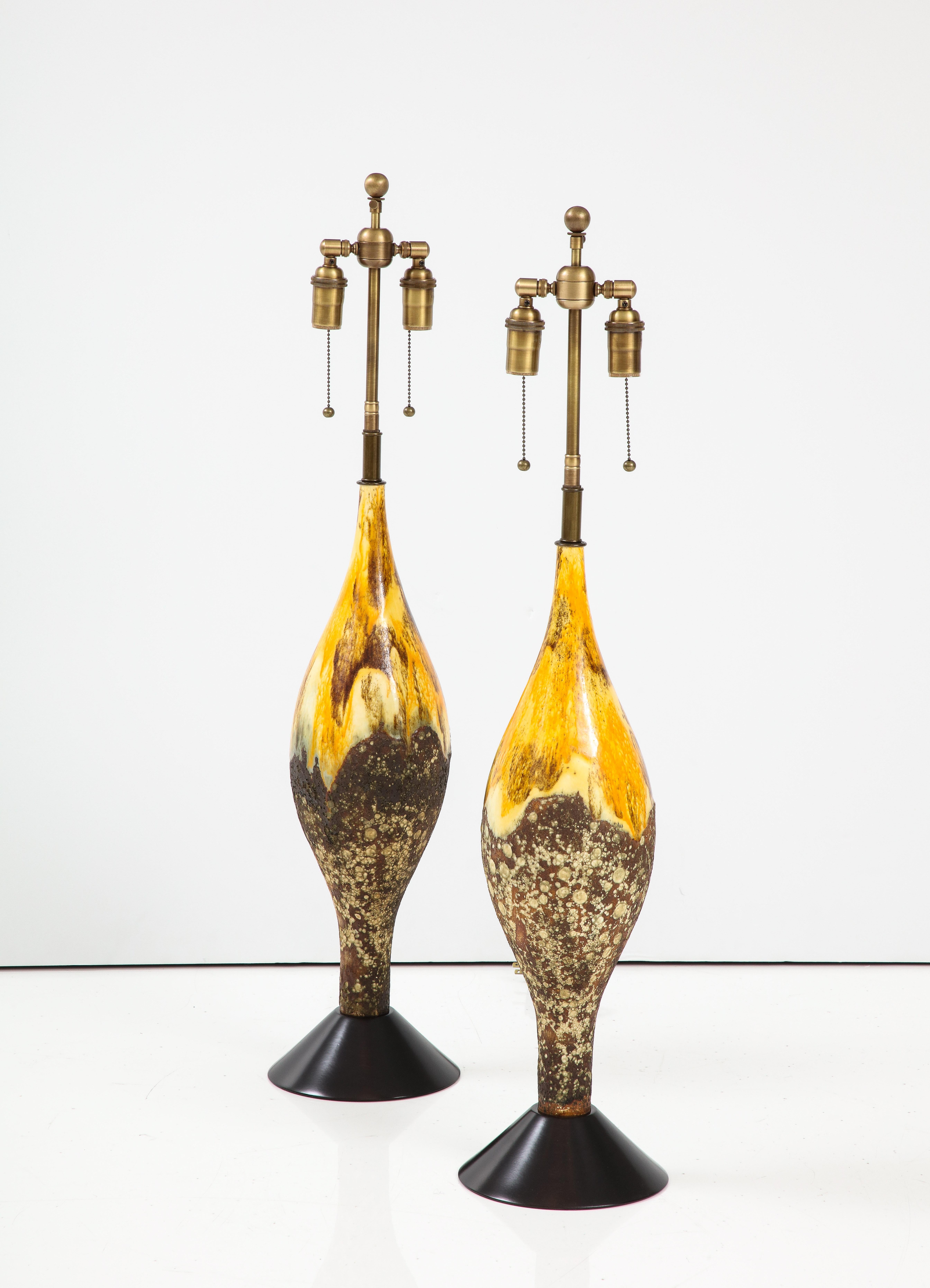 Pair of large Mid-Century ceramic lamps with a wonderful textured Volcanic
glazed finish. The lamps have been newly rewired with adjustable polished brass double clusters that take standard size light bulbs.
The height to the top of the ceramic is