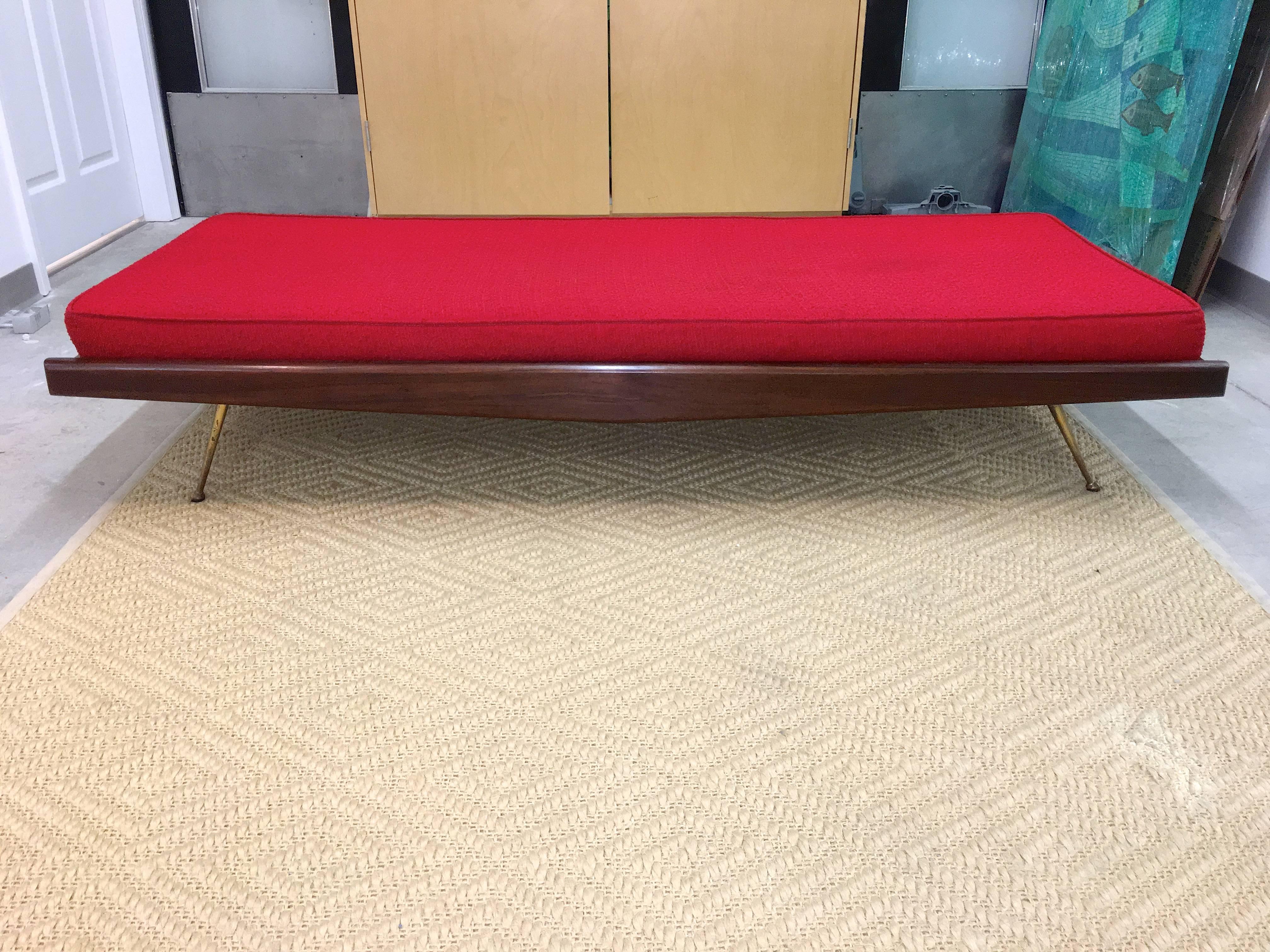 A pair of 1960s walnut daybeds in the style of Robsjohn-Gibbings. Walnut frame with distinctive diamond form walnut panel on one side of each daybed. Flat spring stretched supports with canvas cover. Tapered solid brass legs with half ball feet.