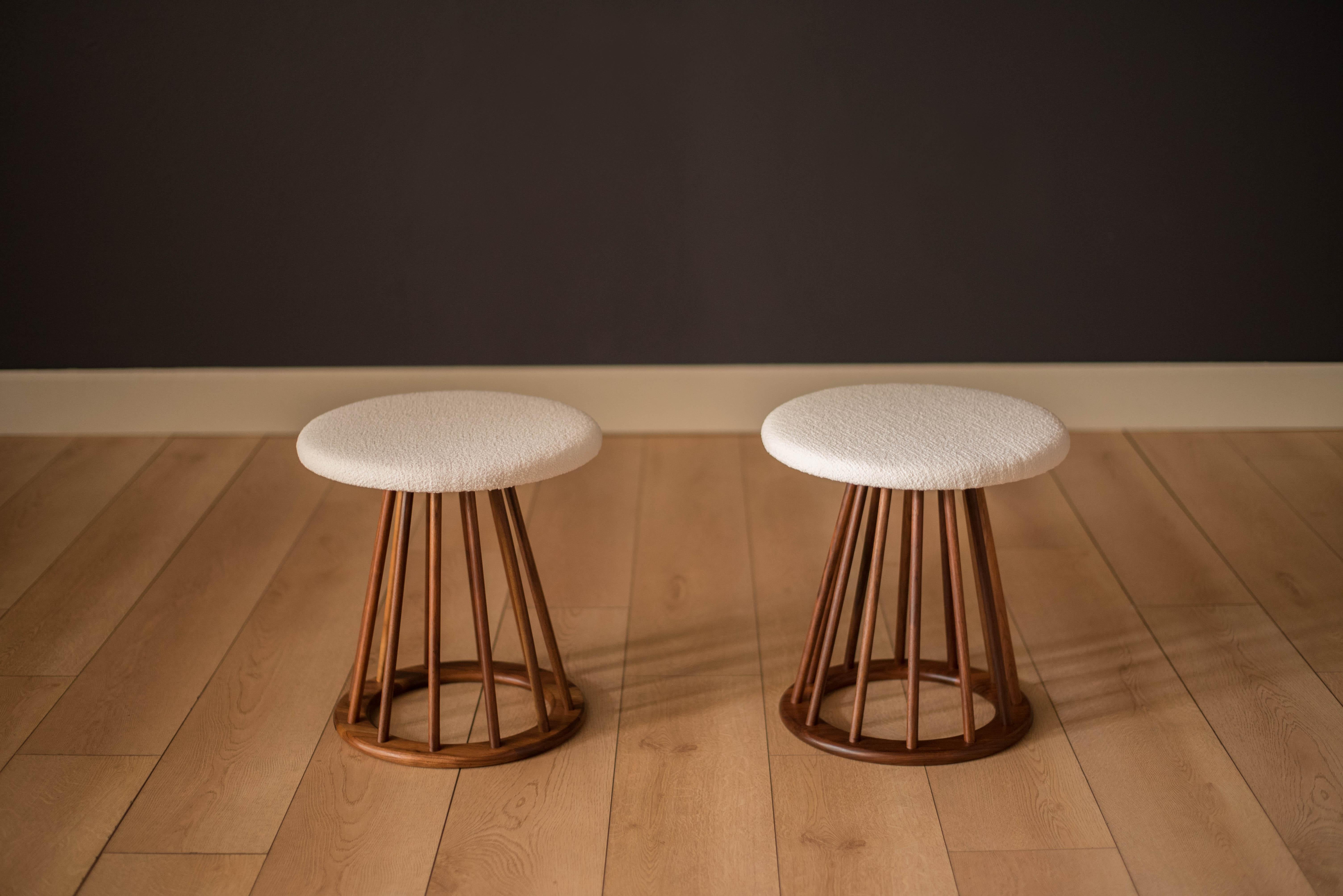 Vintage pair of round spindle stools designed by Arthur Umanoff for Washington Woodcraft. This set is constructed of solid walnut and has been newly reupholstered in a white boucle fabric. Perfect to use as ottomans, extra seating, or side tables