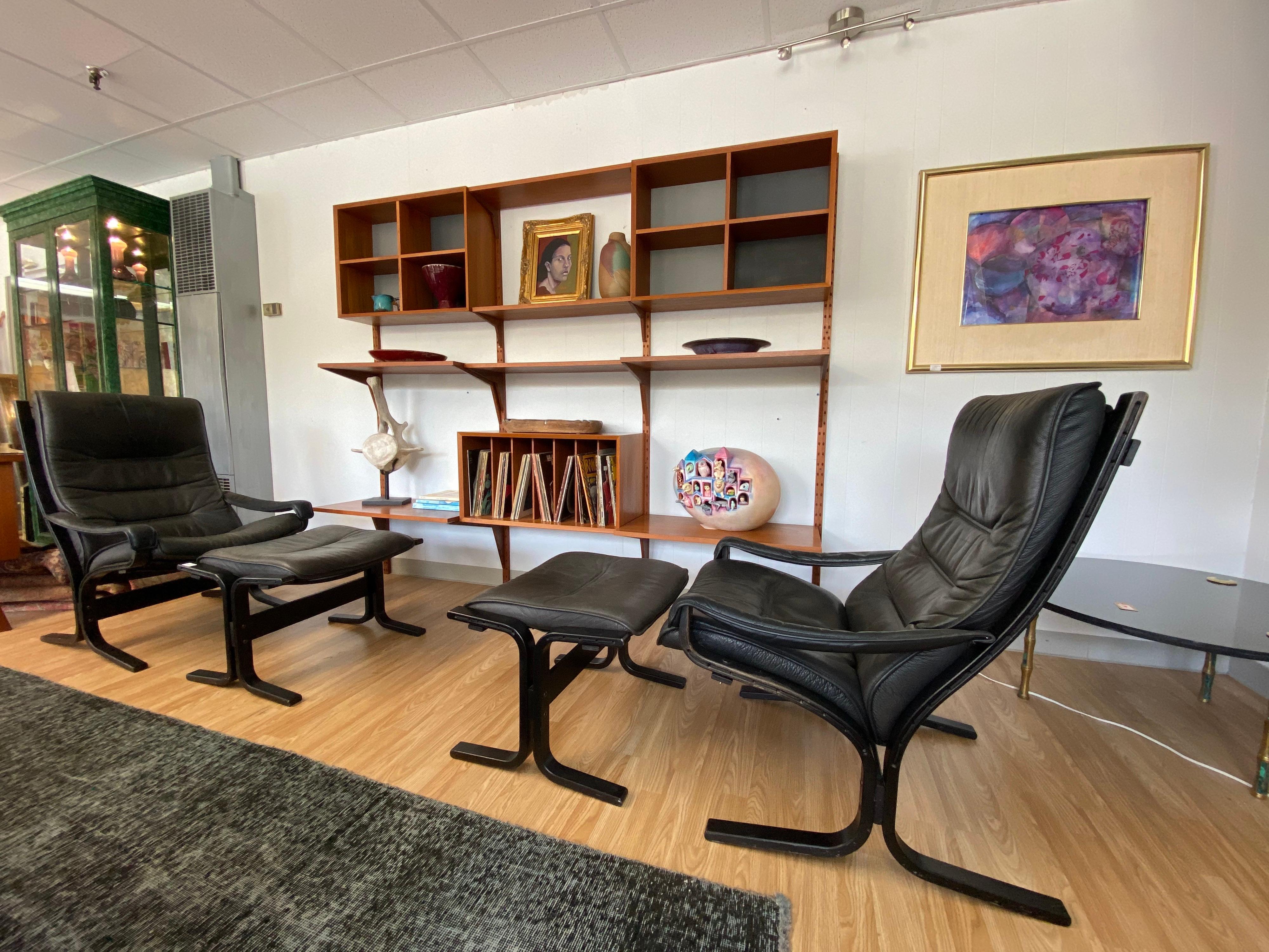 Pair of modern Westnofa Siesta high-back lounge chairs with arms and matching ottomans in a bentwood frame and leather in light black color show age-appropriate patina, circa 1970s. Both lounge chairs come with an ottoman and are sold as a set.