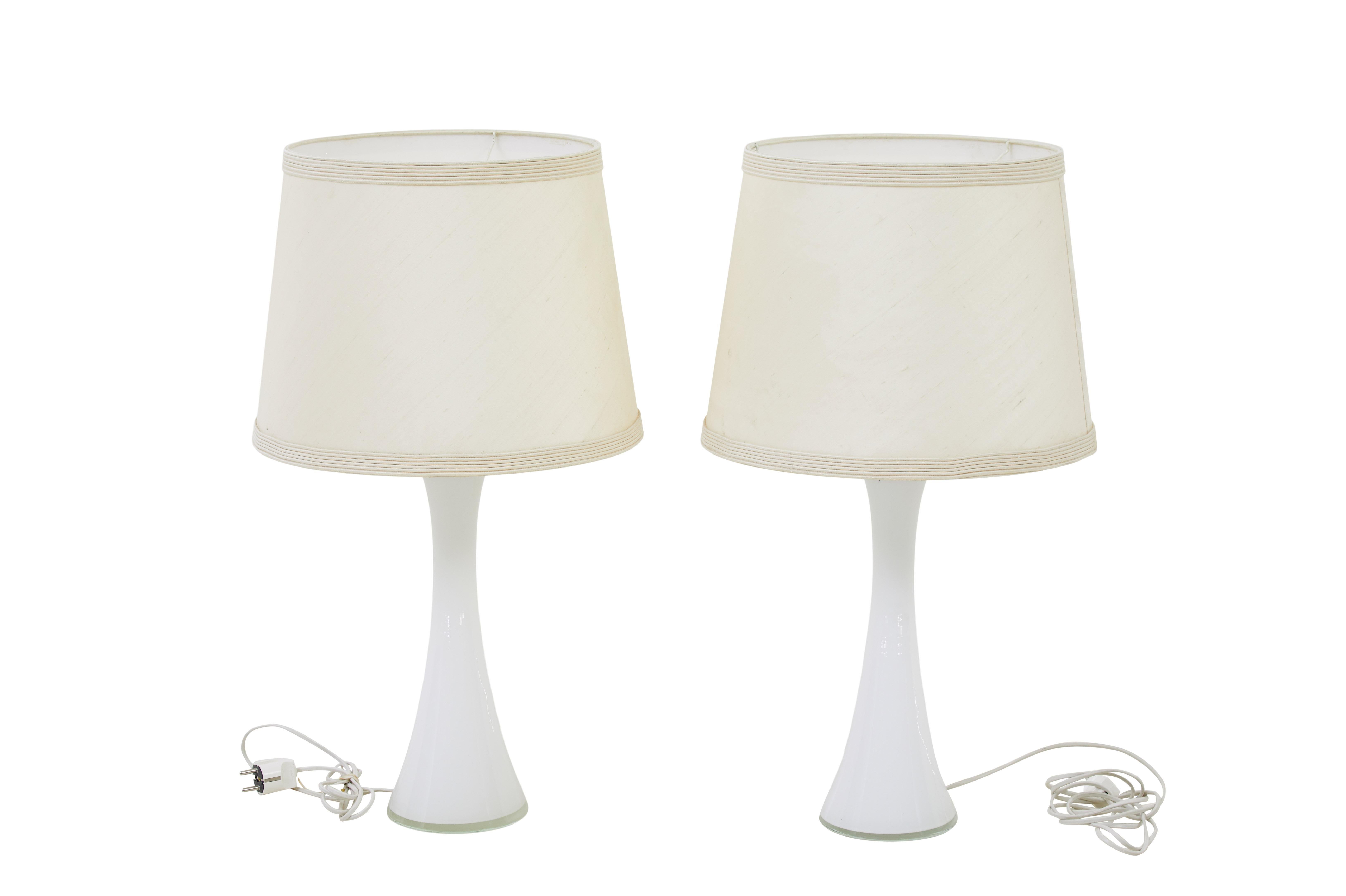 Pair of 1960's white glass table lamps by bergboms circa 1960.

Good quality pair of Bergboms table lights designed by Bernt Nordstedt.   Gentle diabolo shaped, made in white glass with a teak collar on the top to support the light fittings. 