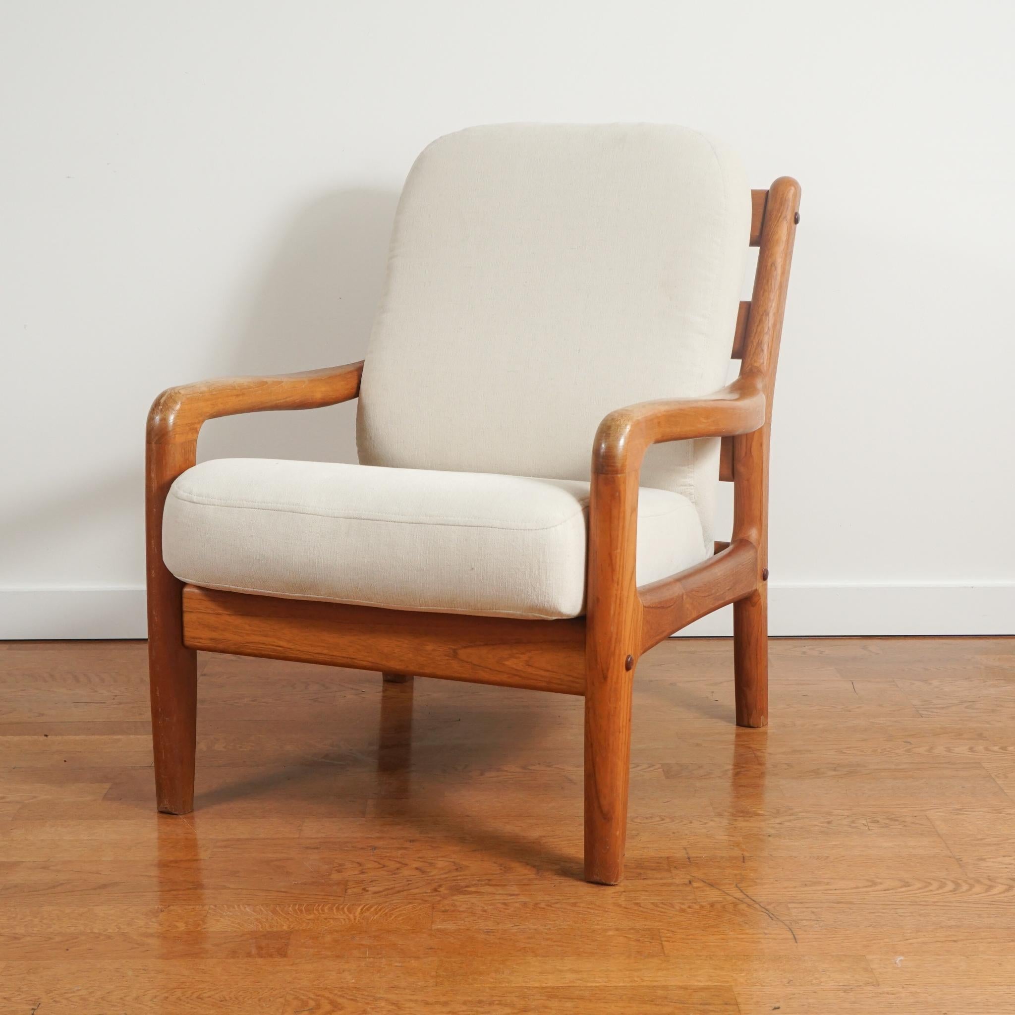 The pair of Danish modern arm chairs, shown here, were made in the 1960s.  The solidly built chairs retain their original wood finish and show only slight wear.  The seat and back cushions are beautifully tailored in a cream colored woven upholstery