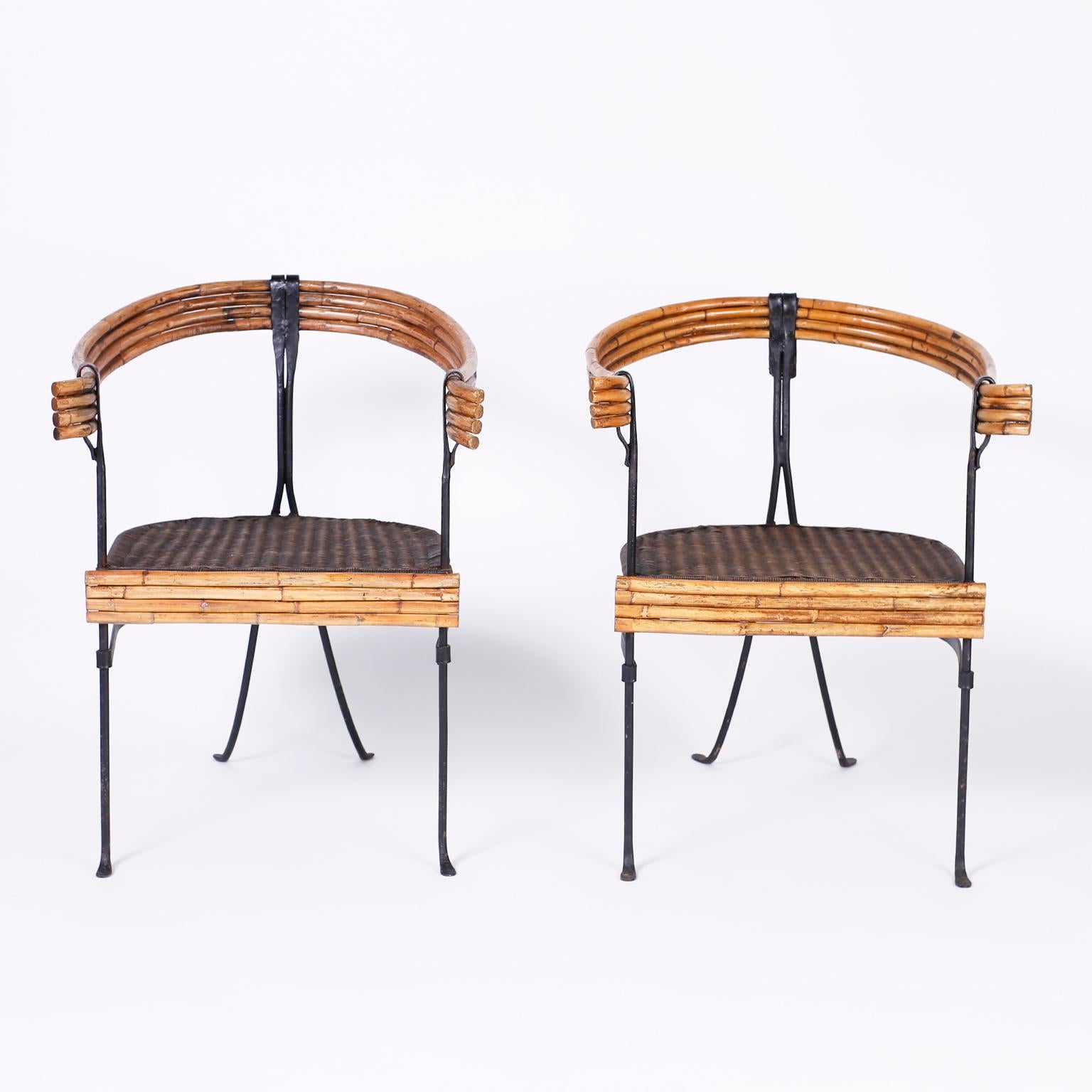 Pair of sculptural Minimalist midcentury armchairs with handwrought iron frames, bamboo skirt, bent bamboo back and arms and a woven caned seat.