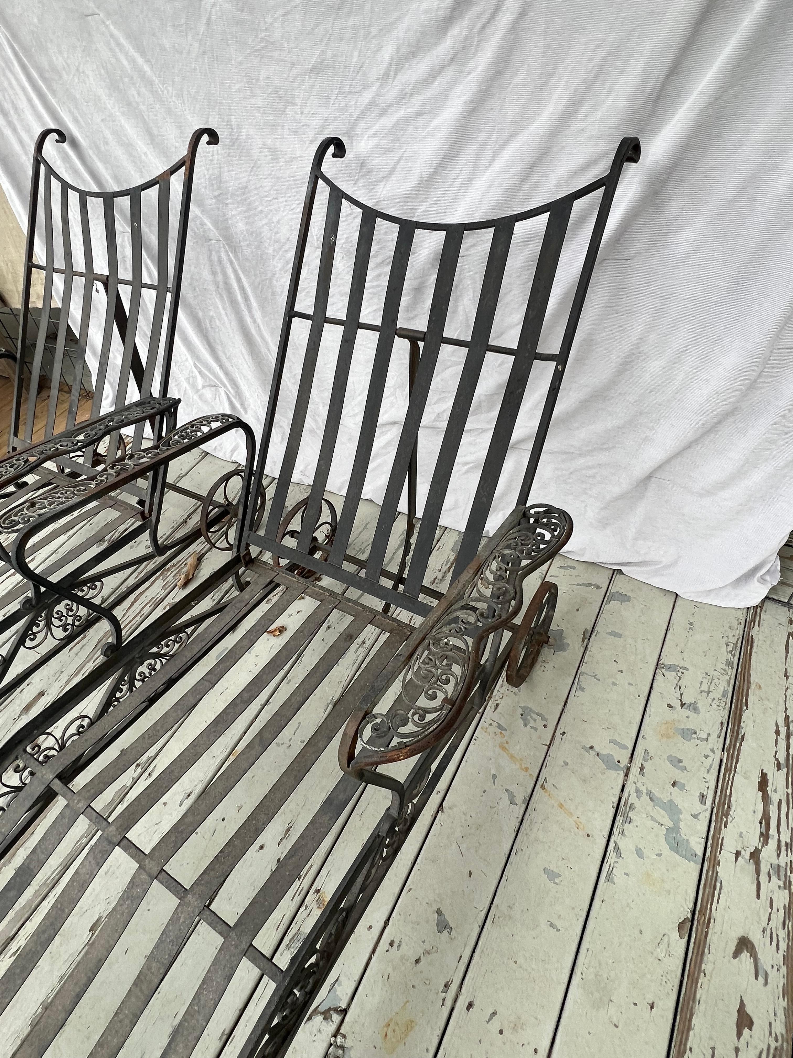 A pair of wrought iron chaise lounges attributed to Salterini from the mid 20th century.  These finely wrought lounges have a beautiful overall scroll pattern and adjustable backs and wheels for easy transport.  They are very decorative and