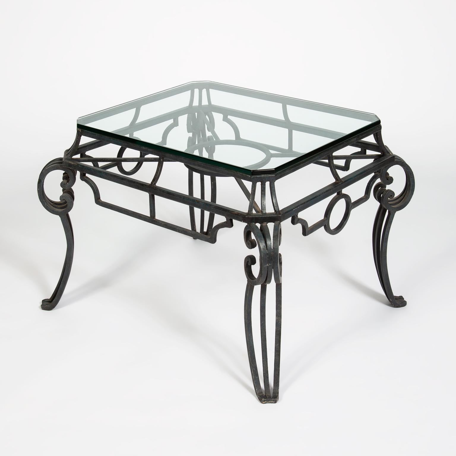 A pair of French midcentury wrought iron side tables with thick glass tops. The metal work has natural signs of patination from age.
