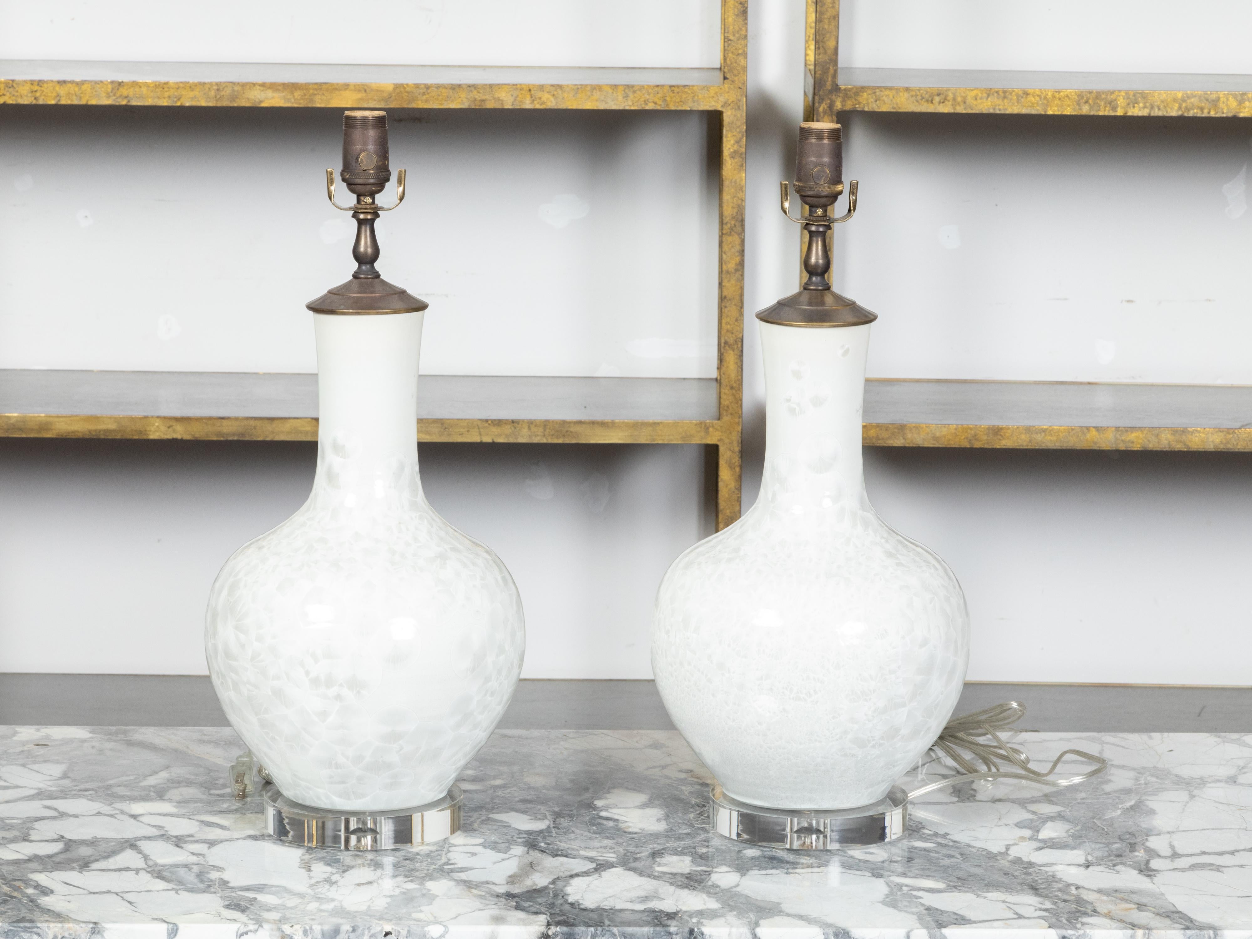 A pair of Asian white porcelain table lamps with textured effects, custom made circular lucite bases and professional rewiring for the US. Created in Asia each of this pair of table lamps features a white porcelain vase with narrow neck and generous