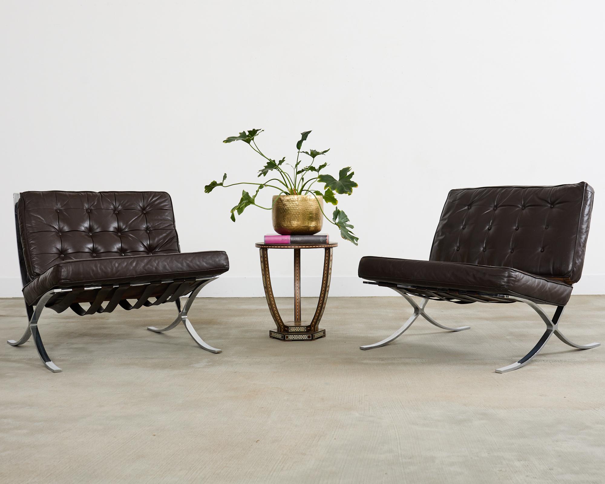 Iconic pair of Mid-Century Modern Barcelona chairs made in the manner and style of Ludwig Mies Van der Rohe for Knoll. The chairs feature tufted leather seat cushions with a desirable aged patina in a dark chocolate or espresso color. The gracefully