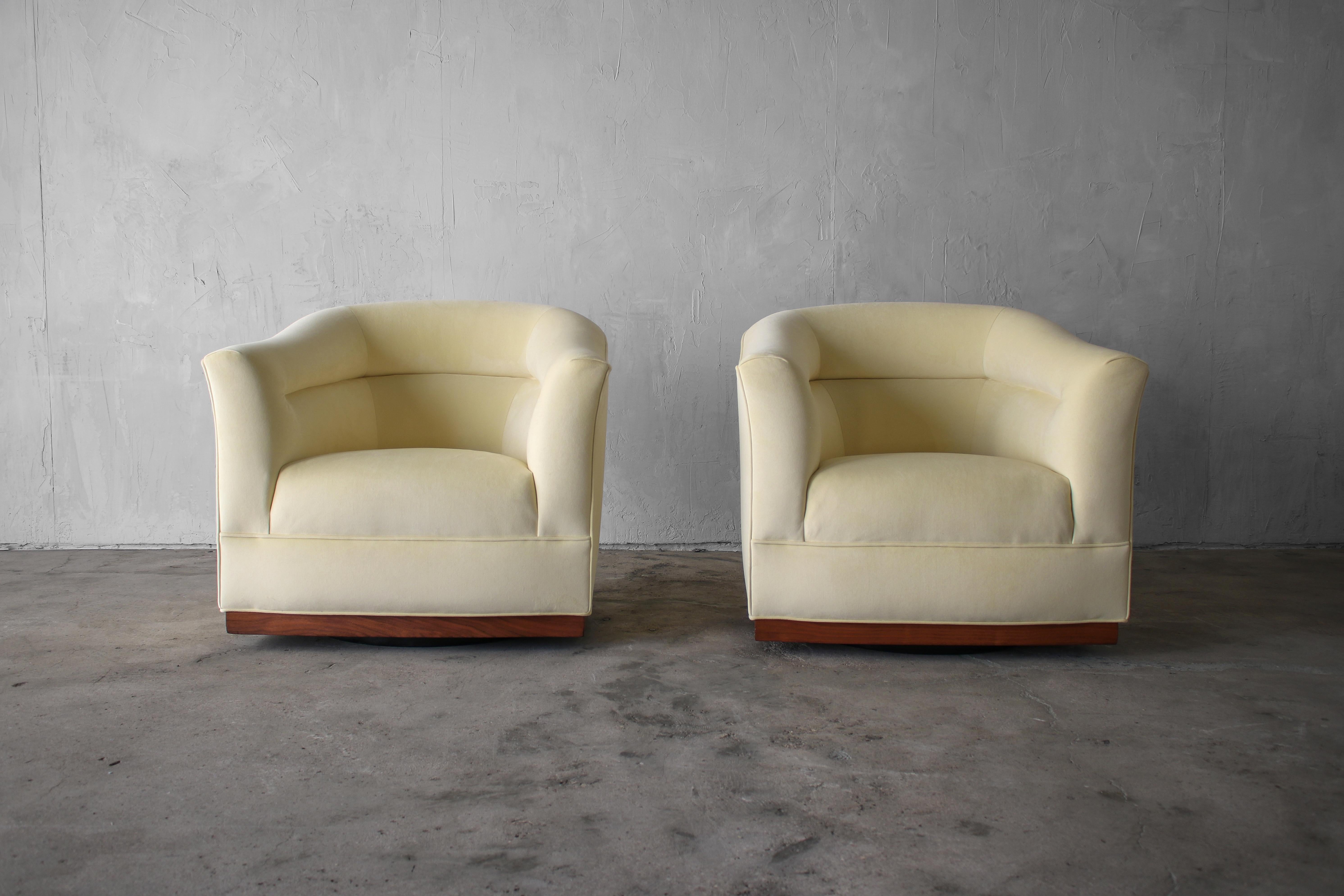 This is a beautiful, large pair of barrel back swivel chairs with walnut trim and plinth swivel bases. This pair has beautiful lines that can be appreciated from almost any angle. 

The chairs have been professionally reupholstered with all new