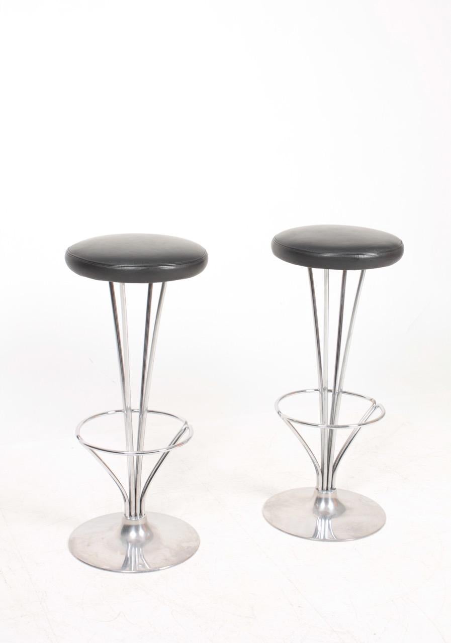 Pair of high stools in metal with patinated leather seats. Designed by Piet Hein for Fritz Hansen. Made in Denmark, great original condition. Ideal for the kitchen or in a bar.
