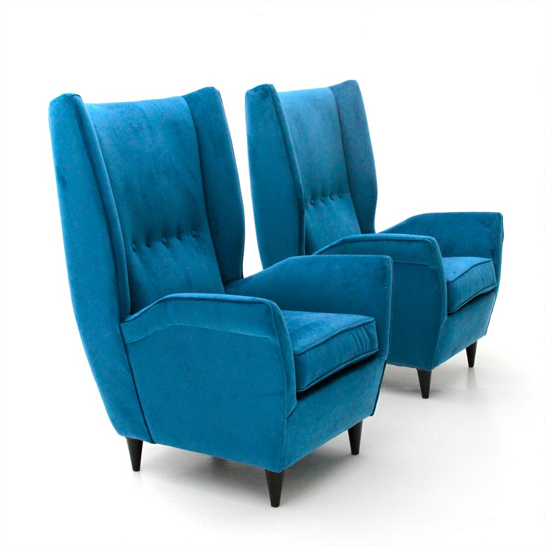 Pair of Italian-made armchairs produced in the 1950s.
Wooden structure padded and lined with new blue velvet fabric.
Seat with cushion.
High back with stitched buttons.
Feet in turned conical wood.
Good general conditions, some signs due to