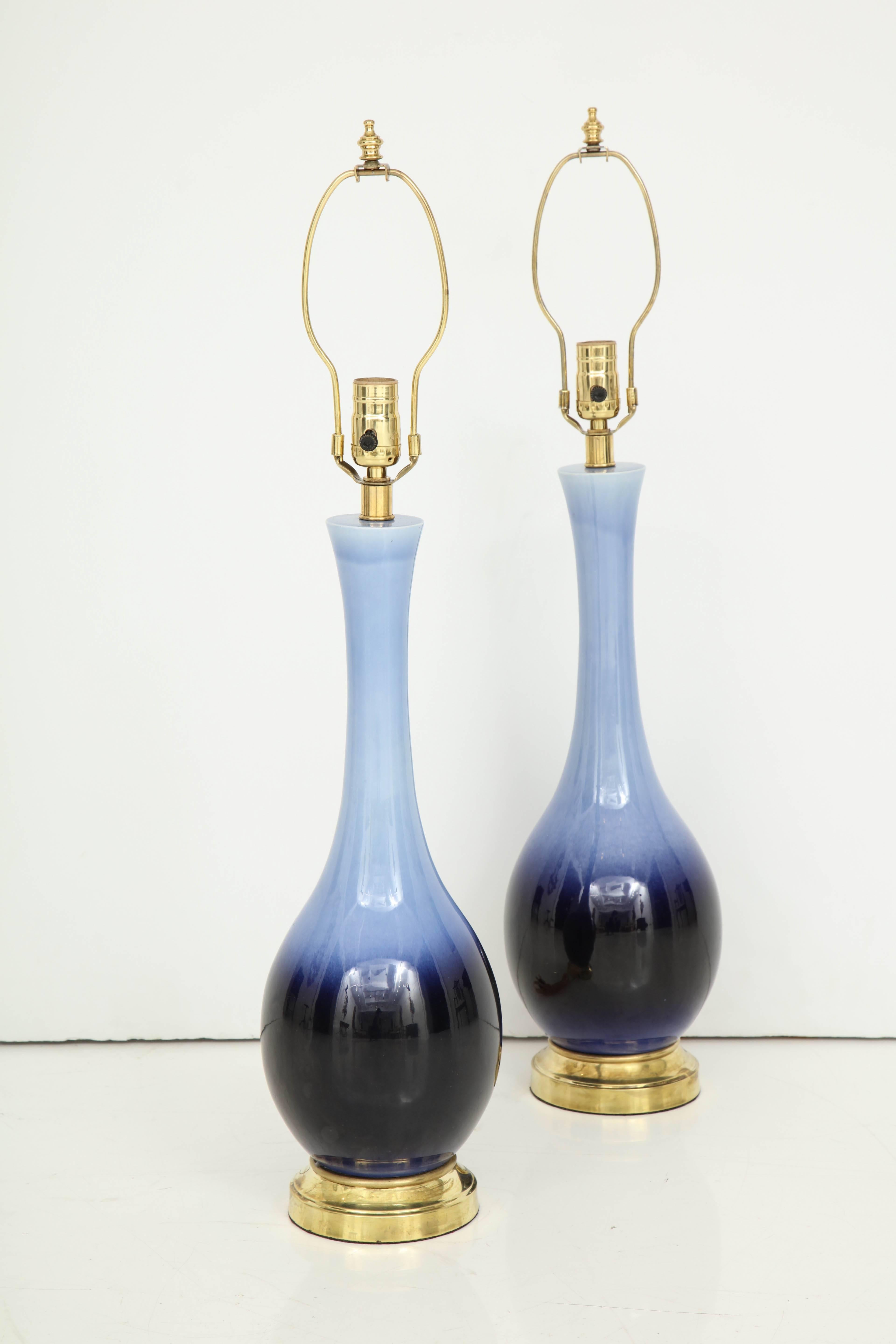 The blue glaze on these lamps transitions from a beautiful soft, pale blue to a deep indigo at the base. The urn shape lamps sit on a brass base and have brass fittings. Recently re-wired.