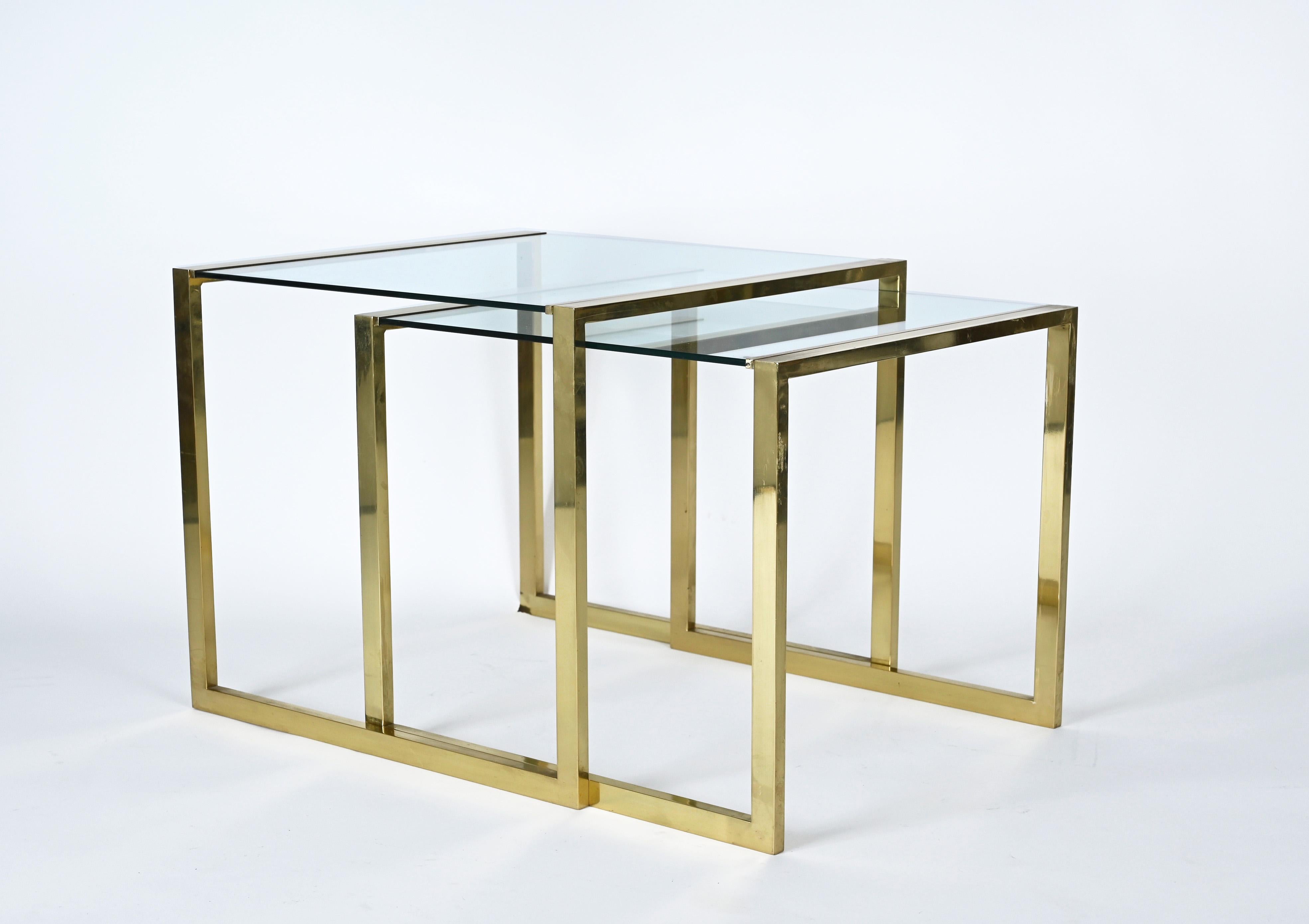 Amazing mid-century brass and crystal glass modern nesting tables. This fantastic piece was produced in Italy during the 1970s.

Very classic midcentury pair of nesting tables from the 70s, with crystal glass tops mounted between the two