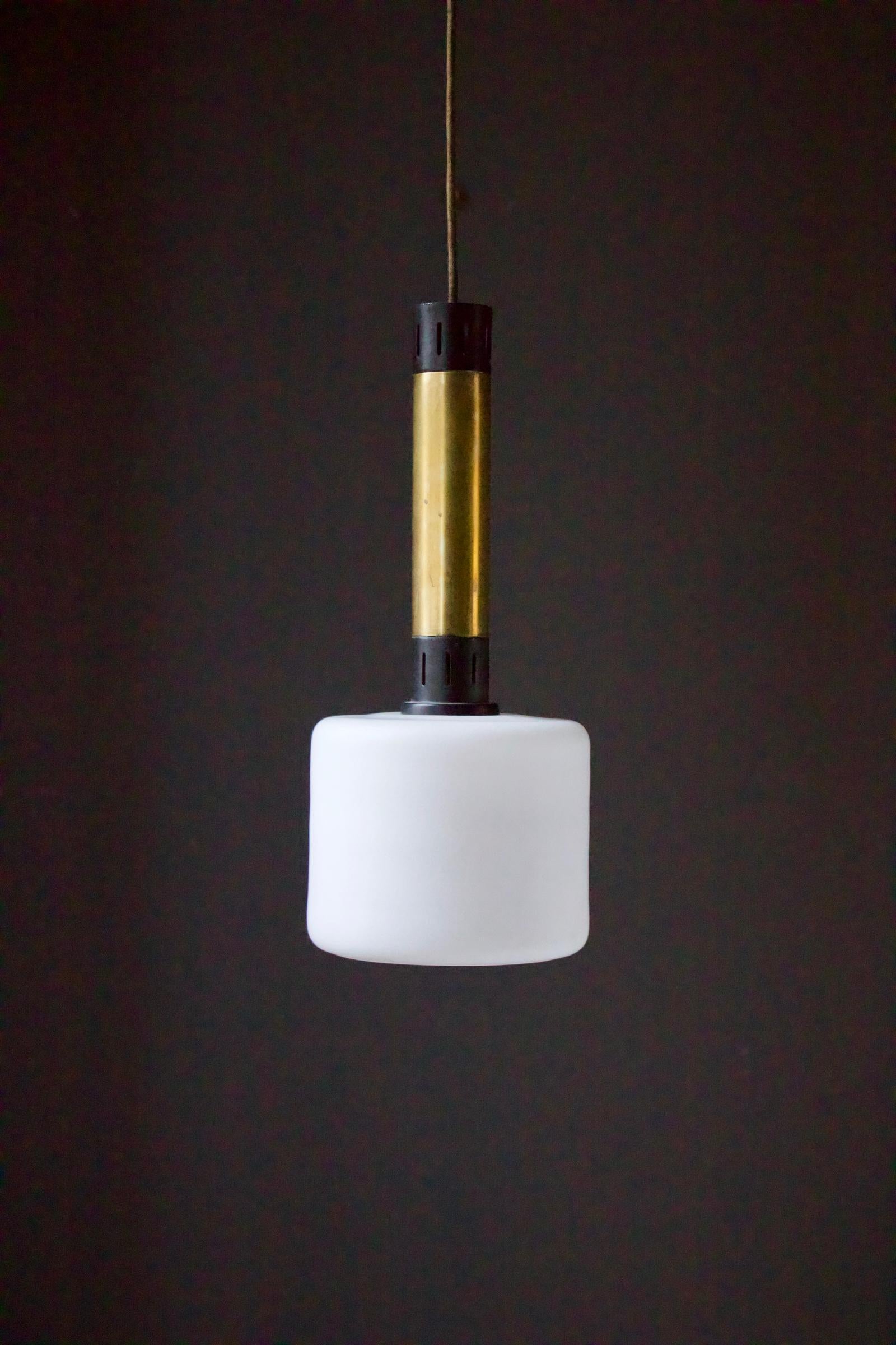 Pair of midcentury brass and satin glass pendant lights attributed Stilnovo, Italy.

The lights each comprise a large shade of white satin glass - which gives a good amount of light - topped with brass tubes and black-finished aluminium sections.