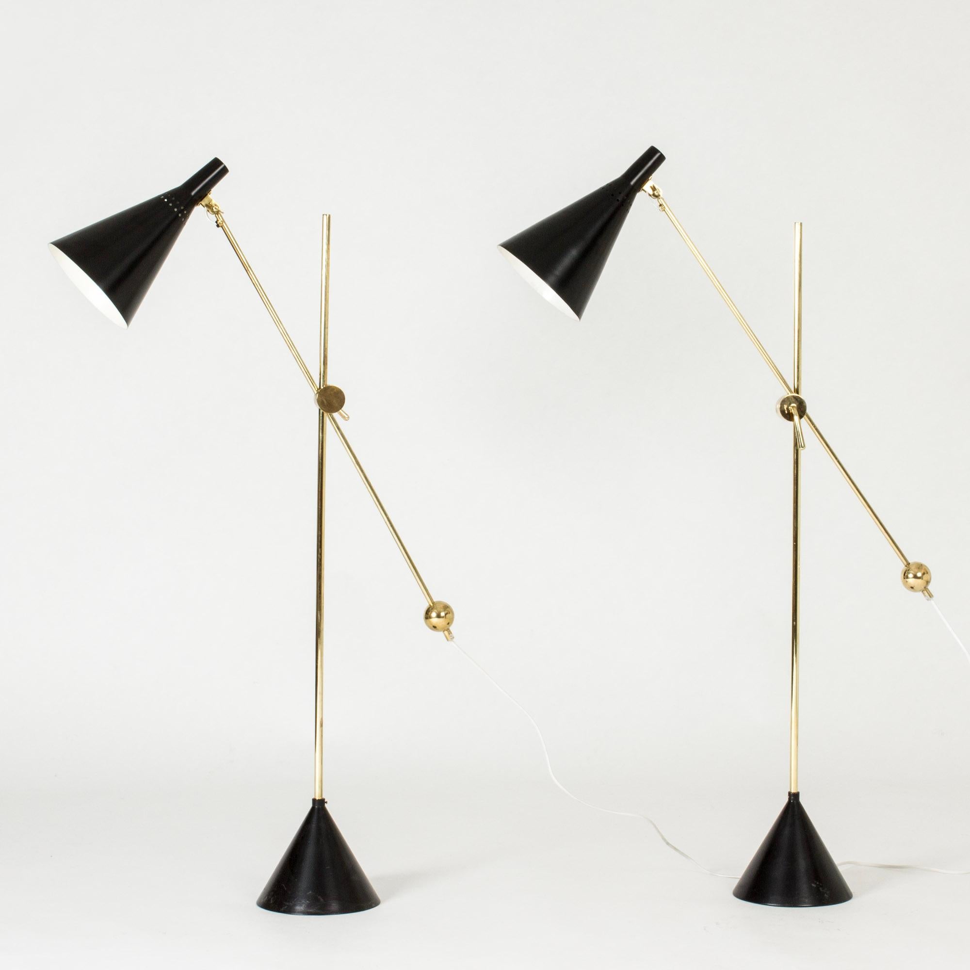 Erstaunliches Paar Stehlampen von Tapio Wirkkala, hergestellt aus Messing und schwarz lackiertem Metall. Schöne dekorative Messingdetails und ein raffinierter Mechanismus zum Verstellen der Höhe und des Winkels der Schirme. Konische Böden.