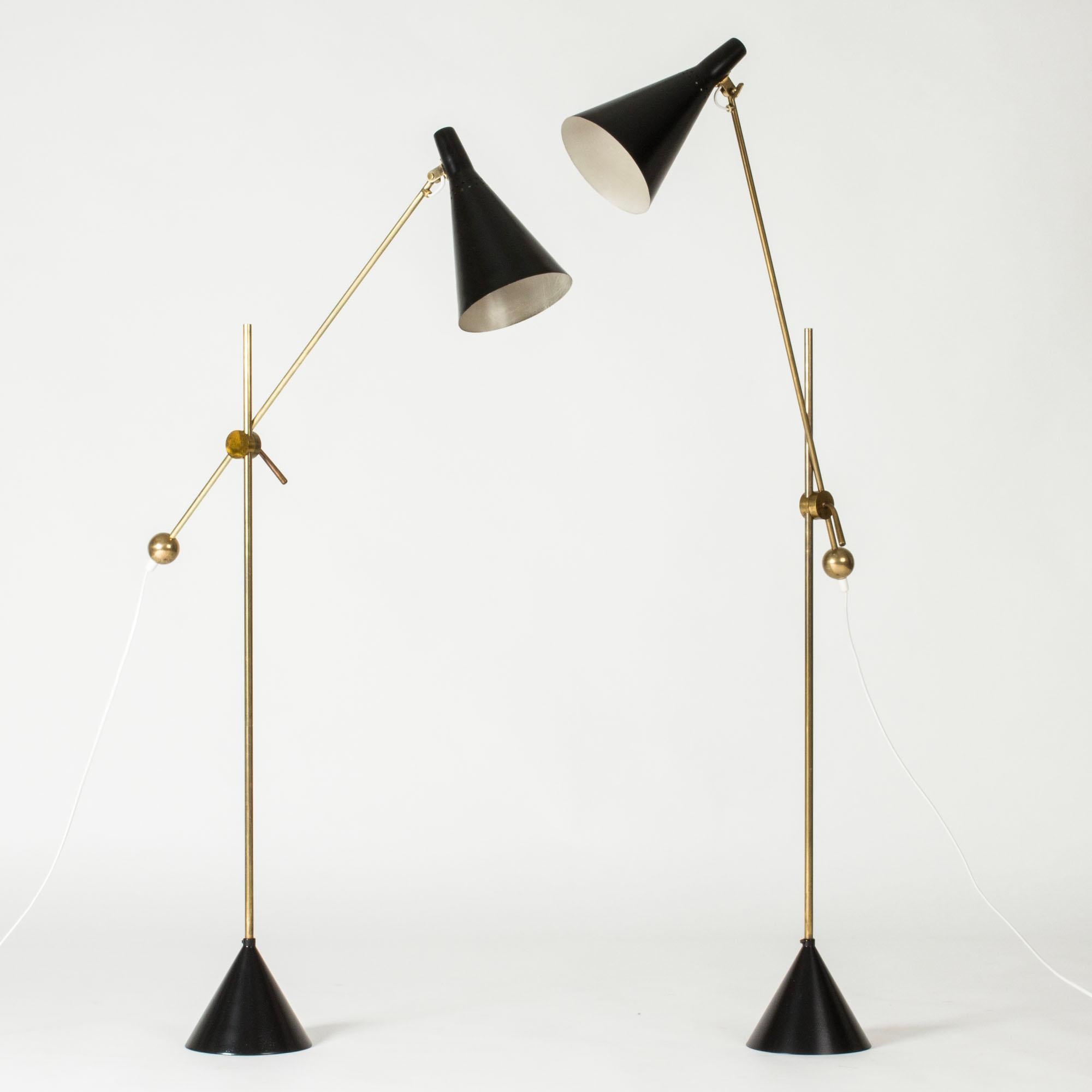 Superbe paire de lampadaires de Tapio Wirkkala, en laiton et métal laqué noir. Magnifiques détails décoratifs en laiton et mécanisme astucieux permettant de modifier la hauteur et l'angle des abat-jour. Bases coniques.