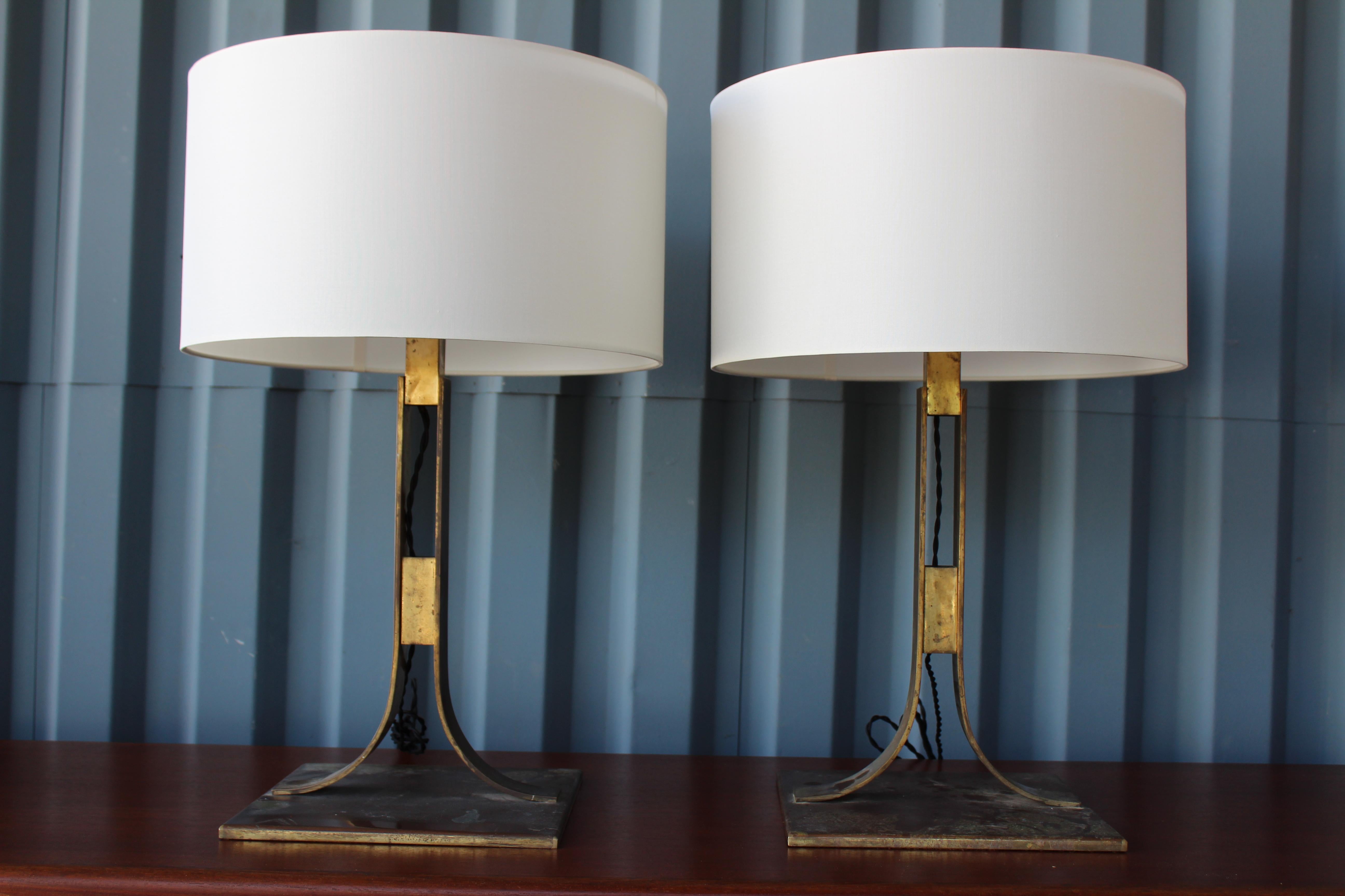 Pair of solid brass table lamps with original heavy patina. Each lamp has two bulbs. The pair have been recently rewired and feature new silk shades with top diffusers.