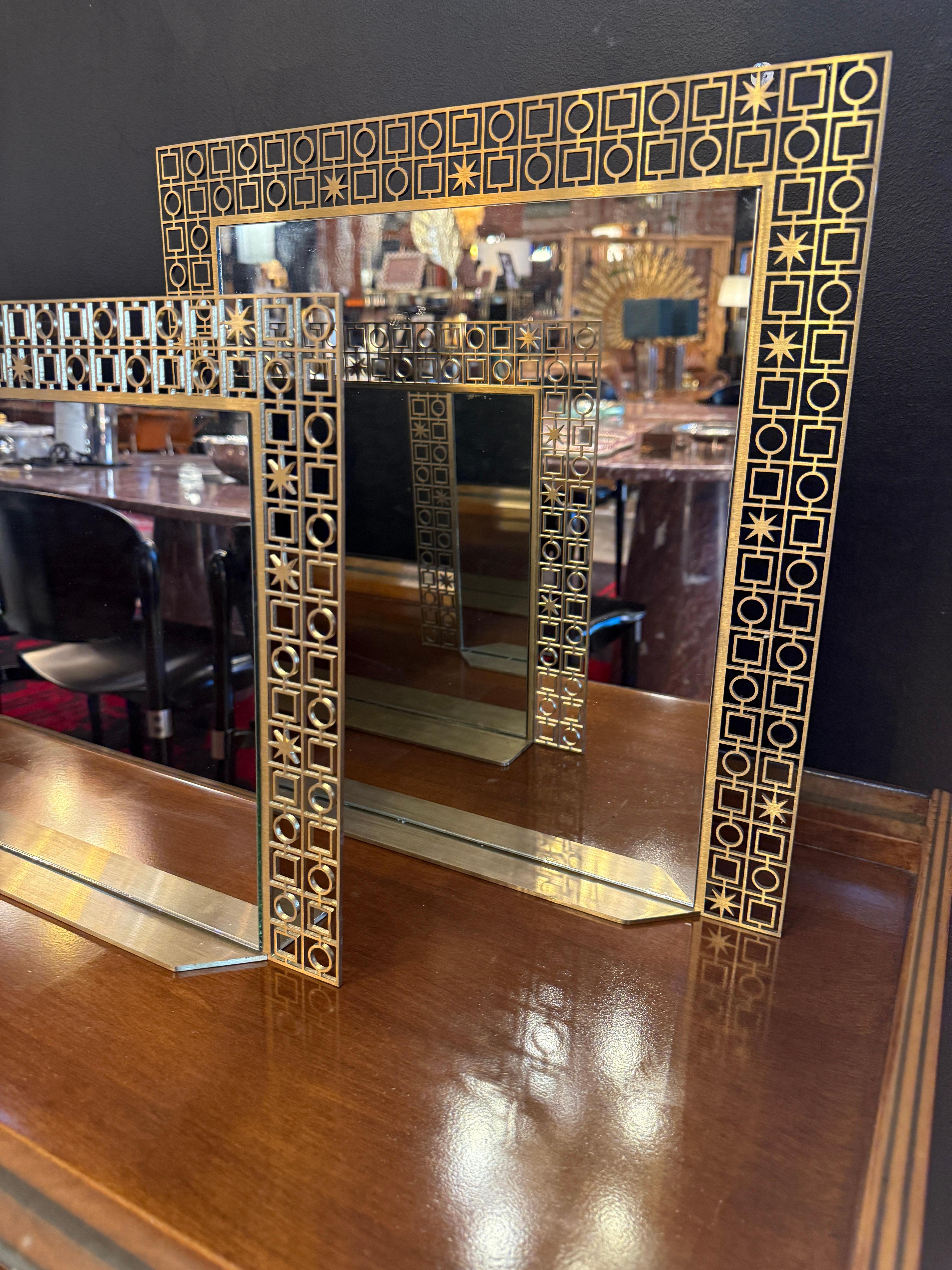 Si tratta di due specchi vintage in ottone provenienti dall'Italia, probabilmente degli anni '70. Sono caratterizzati da eleganti cornici in ottone traforate geometricamente con intricati motivi quadrati e circolari, che creano un'estetica