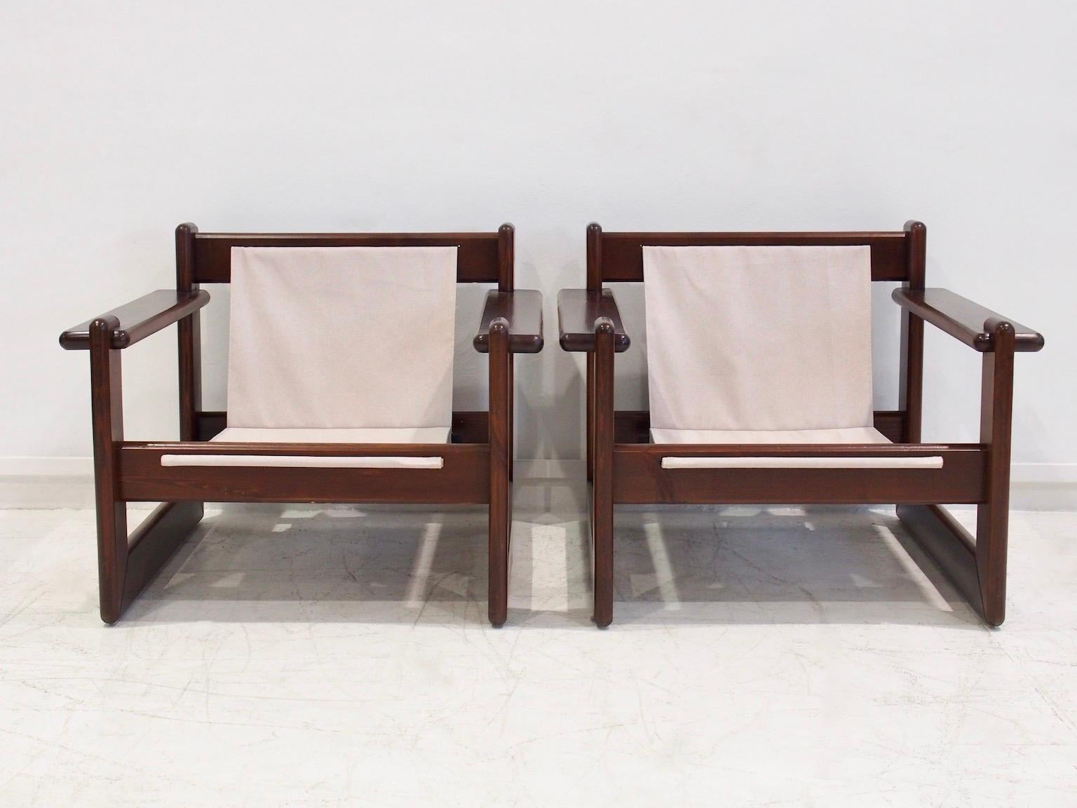 Pareja de sillones de mediados de siglo con estructura de madera de nogal chapada y asientos de tela de lona beige. Fabricado en Brasil hacia la década de 1960. El armazón de las tumbonas se ha repintado y se ha sustituido la tela original. Además,