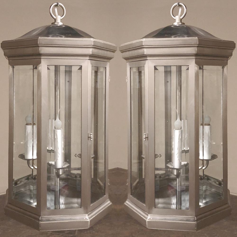Pair of midcentury brushed steel lantern chandeliers were crafted in an octagonal design with beveled glass on each facet, and a rounded pagoda-style roof. Four sockets on bobéches inside ensure abundant light. Made from brushed steel by The