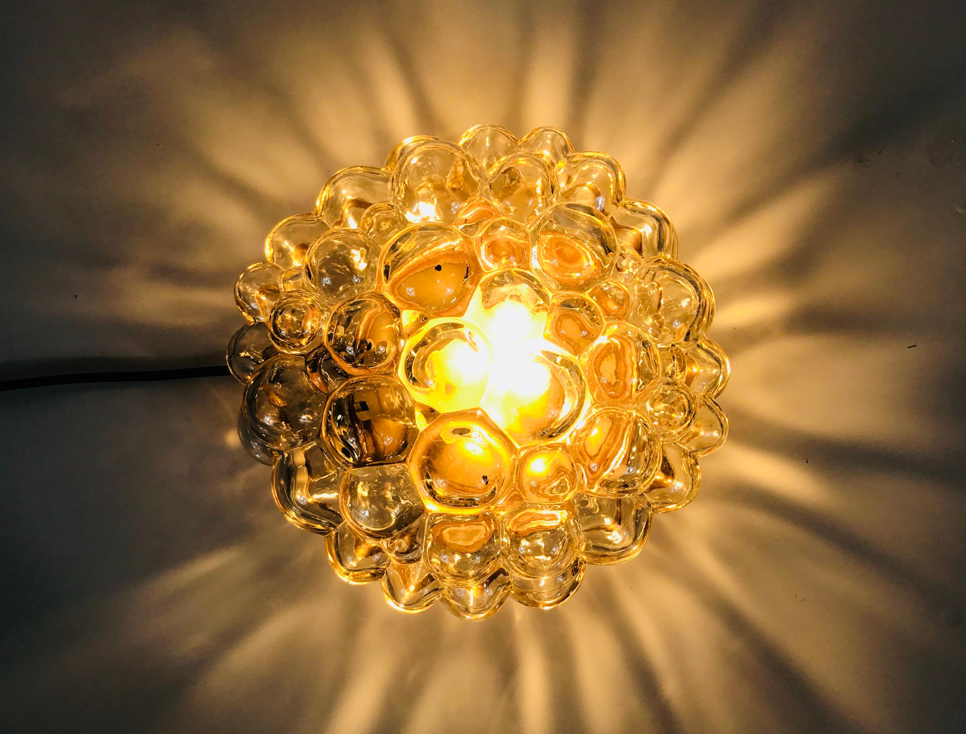 A pair of wall lamps or flush mounts by Glashütte Limburg made in the 1960s. It was designed by Helena Tynell who is famous for the bubble shape. Amber bubble glass shade with brass bottom.

The light requires one E27 light bulb.