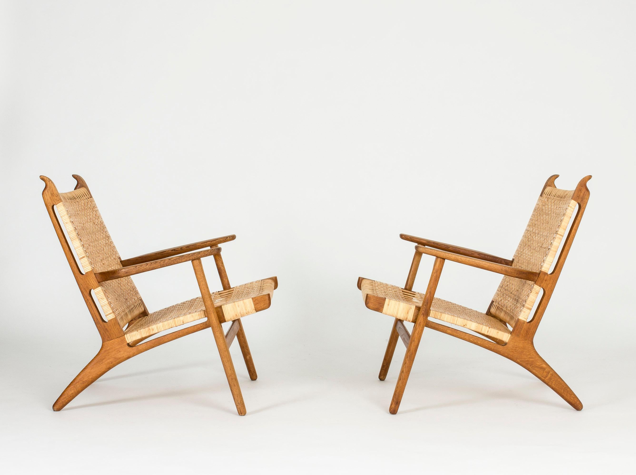 Pair of stunning “CH 27” lounge chairs by Hans J. Wegner, made from oak and rattan. Beautiful pattern in the rattan and whimsical carved “horns” at the top of the back.

Hans J. Wegner designed this model in 1949.