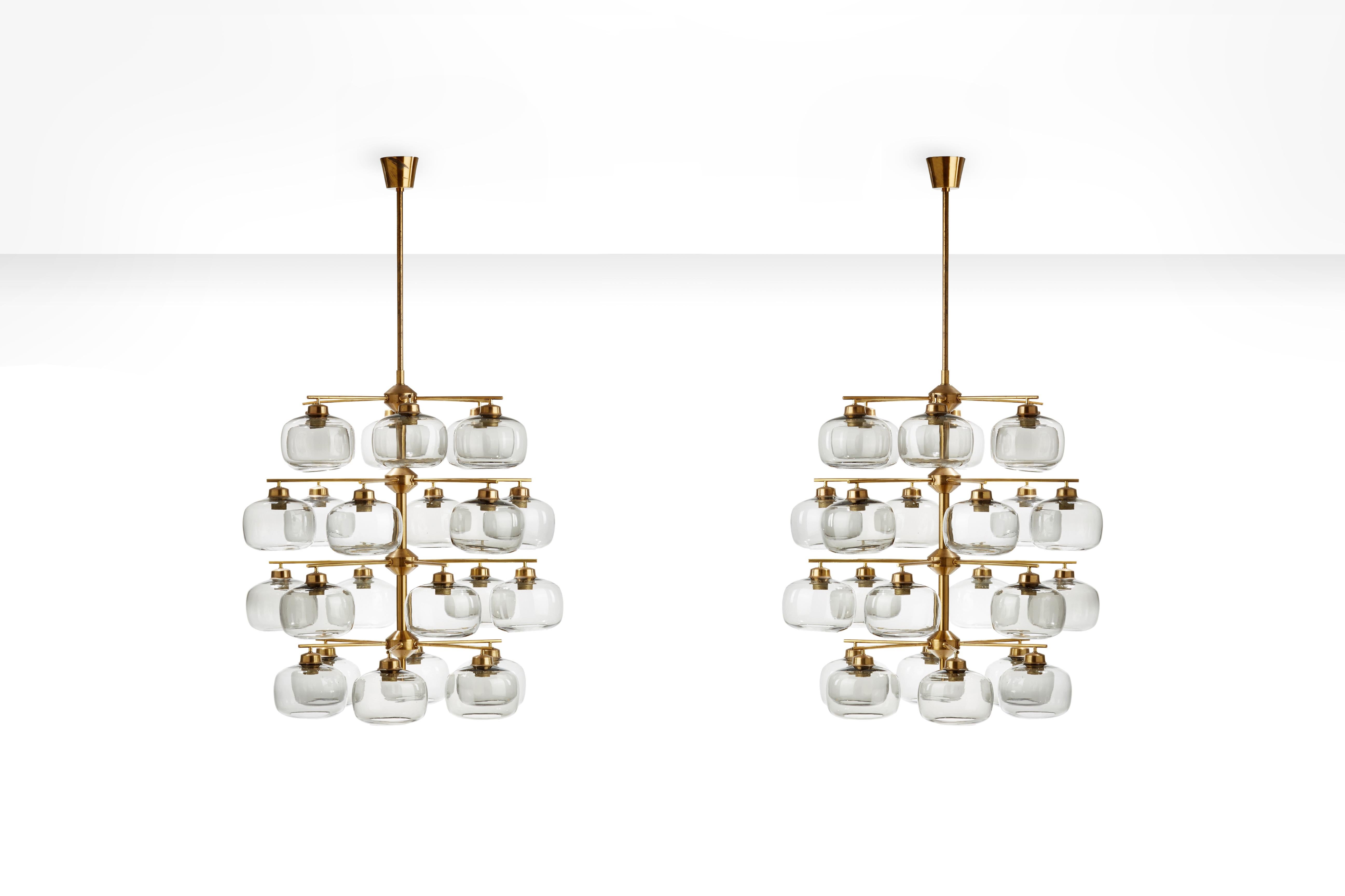 This marvellous pair of chandeliers by Holger Johansson have brass frames and 24 smoked glass shades per item. The lamps have all the characteristics Johansson was famous for: They are elegant, chique, very well produced and although big and shiny