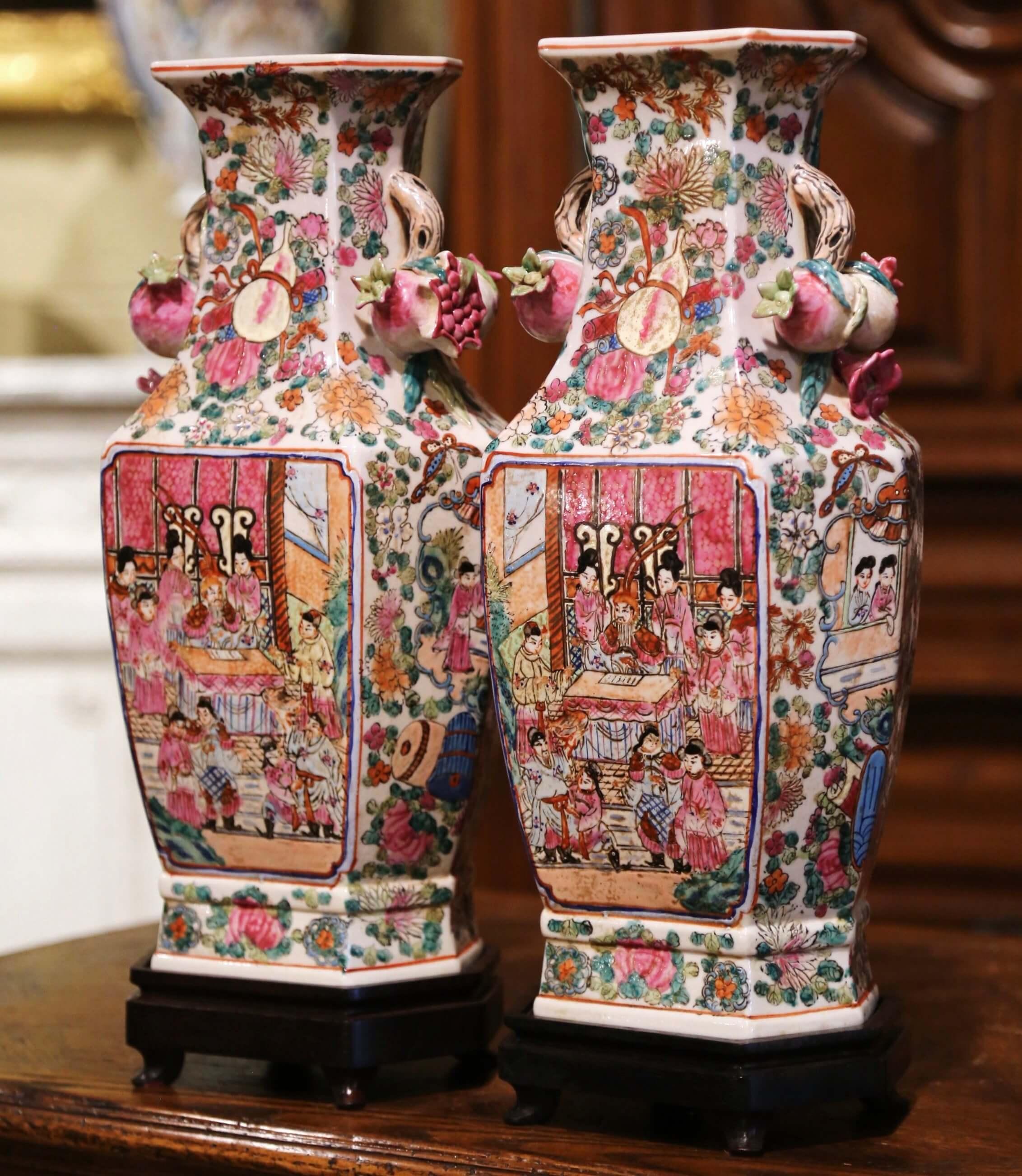 Decorate a mantel with this elegant pair of tall vases on stands. Crafted in China circa 1940, the rose medallion porcelain vases are made of porcelain and embellished with treelike and fruit handles. Each vase stands on a wooden base and is