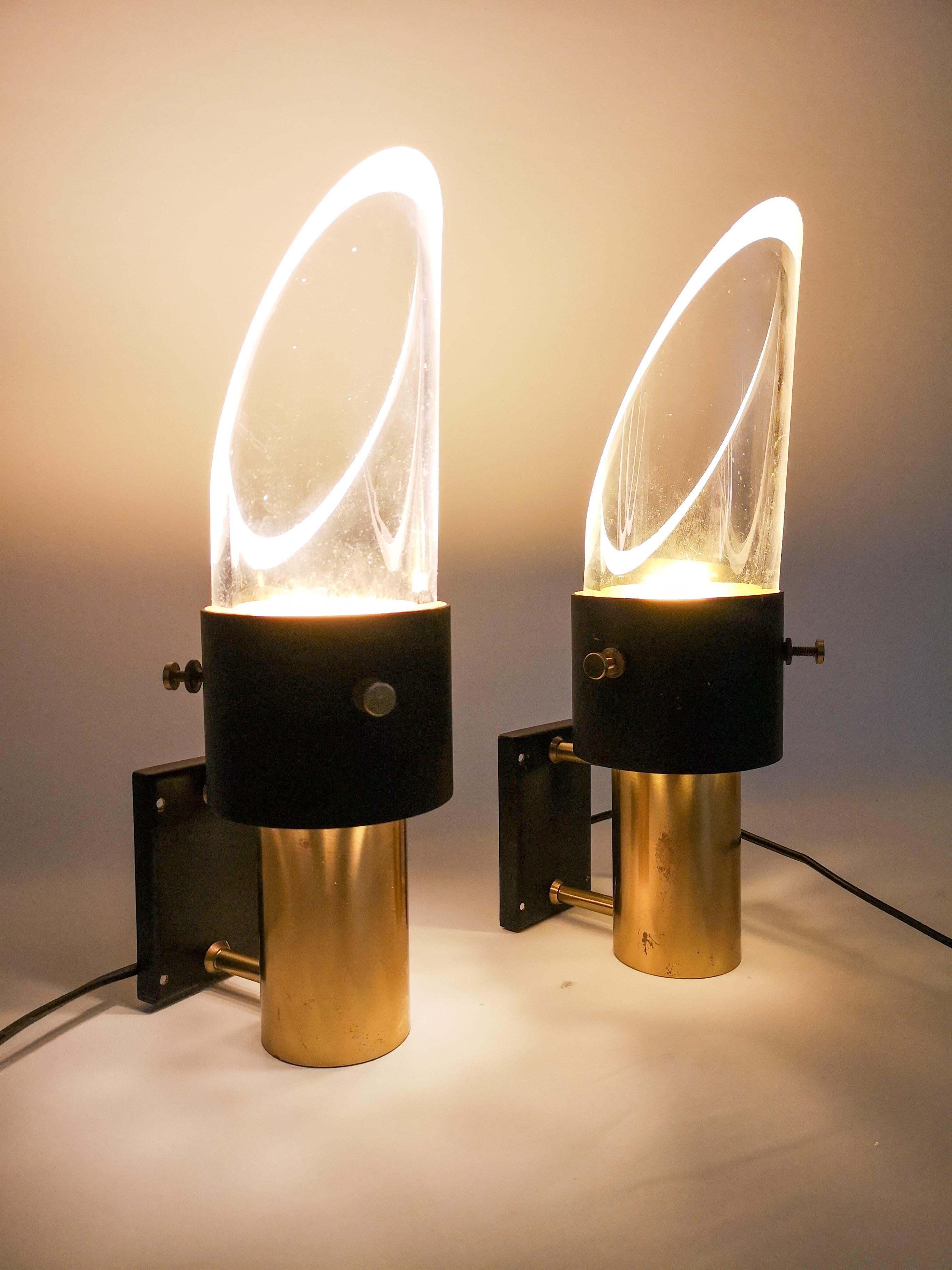 These two midcentury model saga wall lamps was made by Lyfa in Denmark in collaboration with the Swedish company Orrefors. It is made of metal, brass and crystal glass. The wall lamp can be placed upside down and vice versa. The lamp is labeled Lyfa