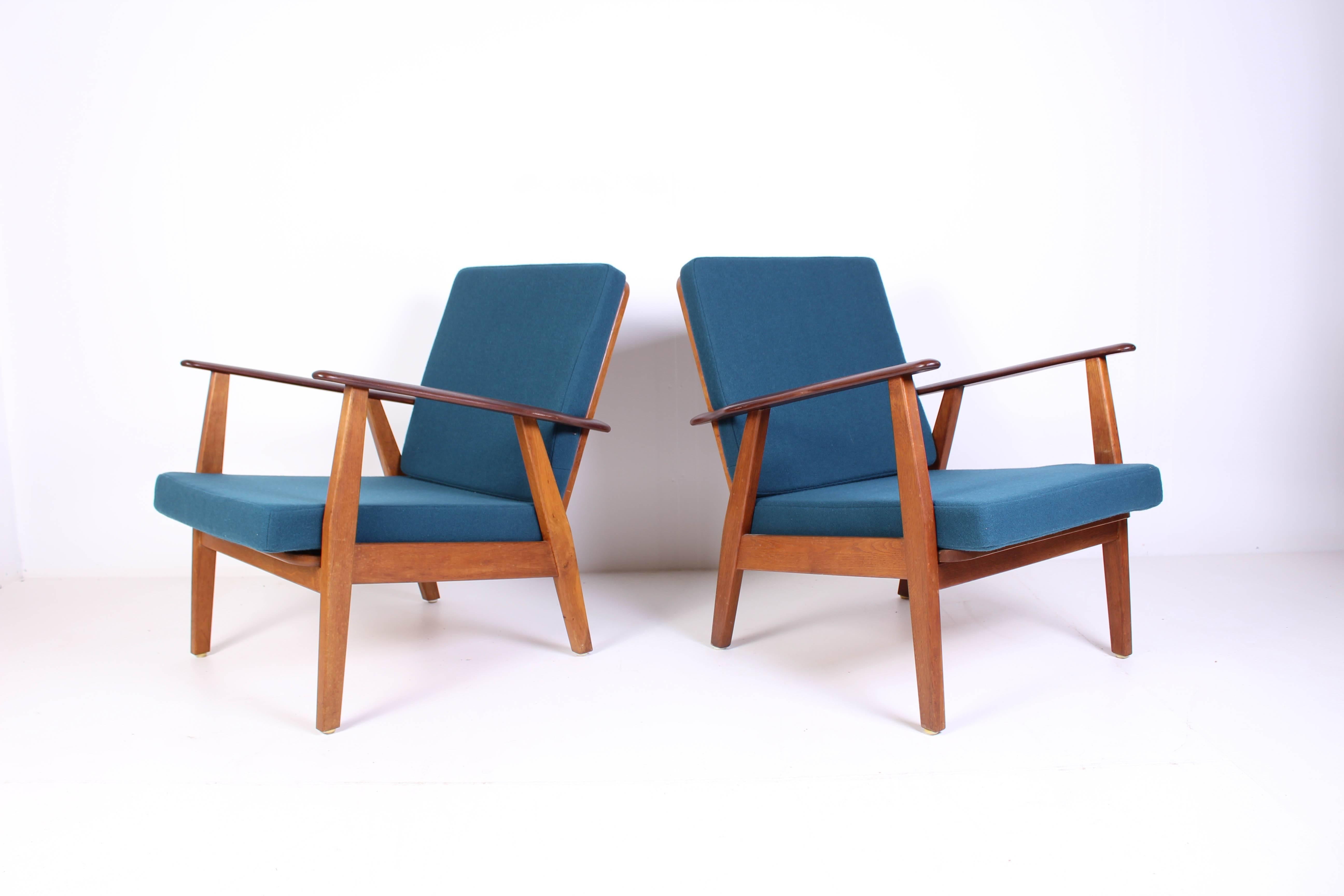 A set of nice Danish lounge chairs with new cushions upholstered with petroleum blue fabric. The chairs are made out of an oak frame with teak armrests. Very good vintage condition with signs of usage consistent with age.
