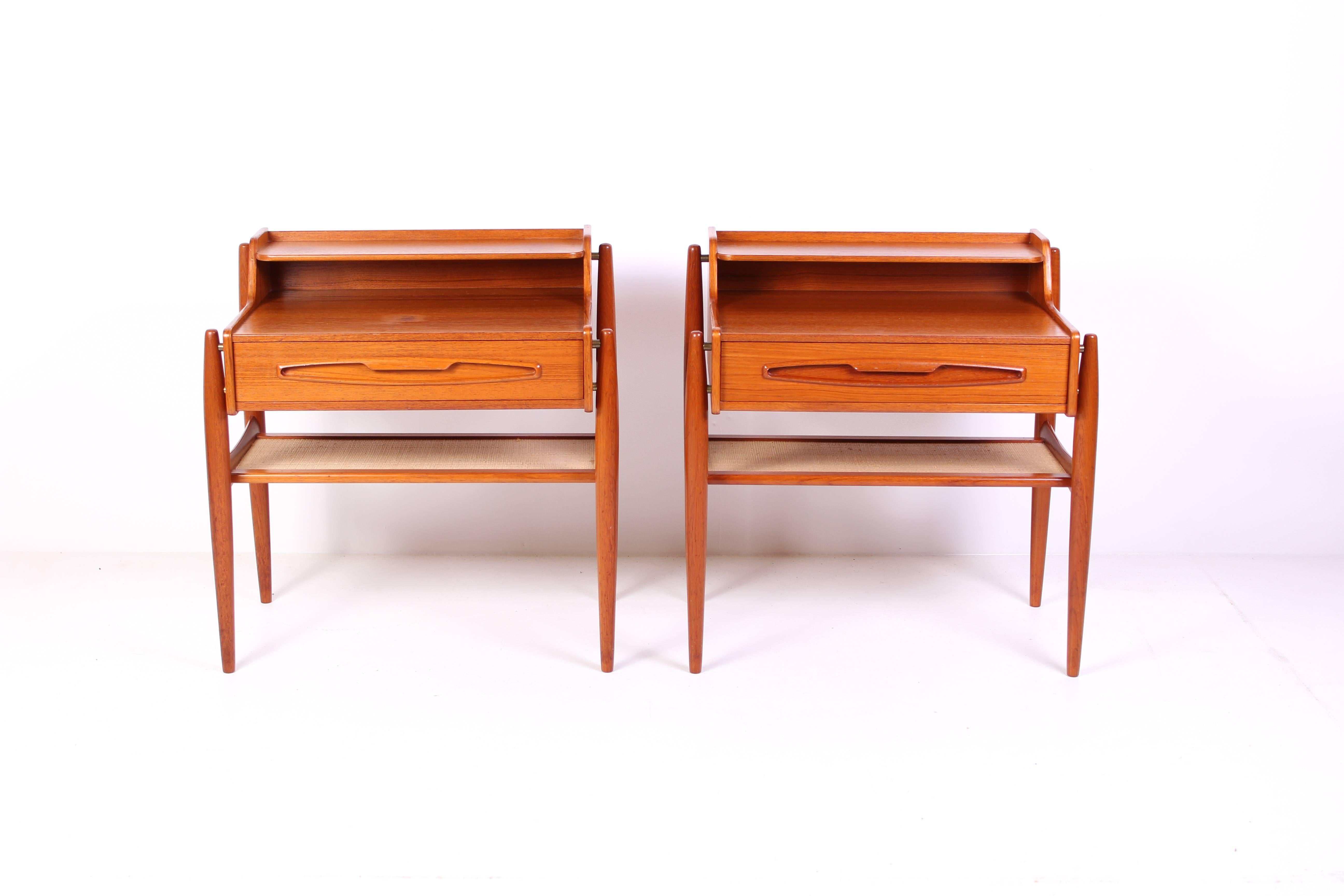 A pair of midcentury Danish nightstands made out of teak with brass details and rattan shelf. The nightstands are likely designed by Arne Vodder. 

Very good vintage condition but there are two darker spots on one of the night stands (see
