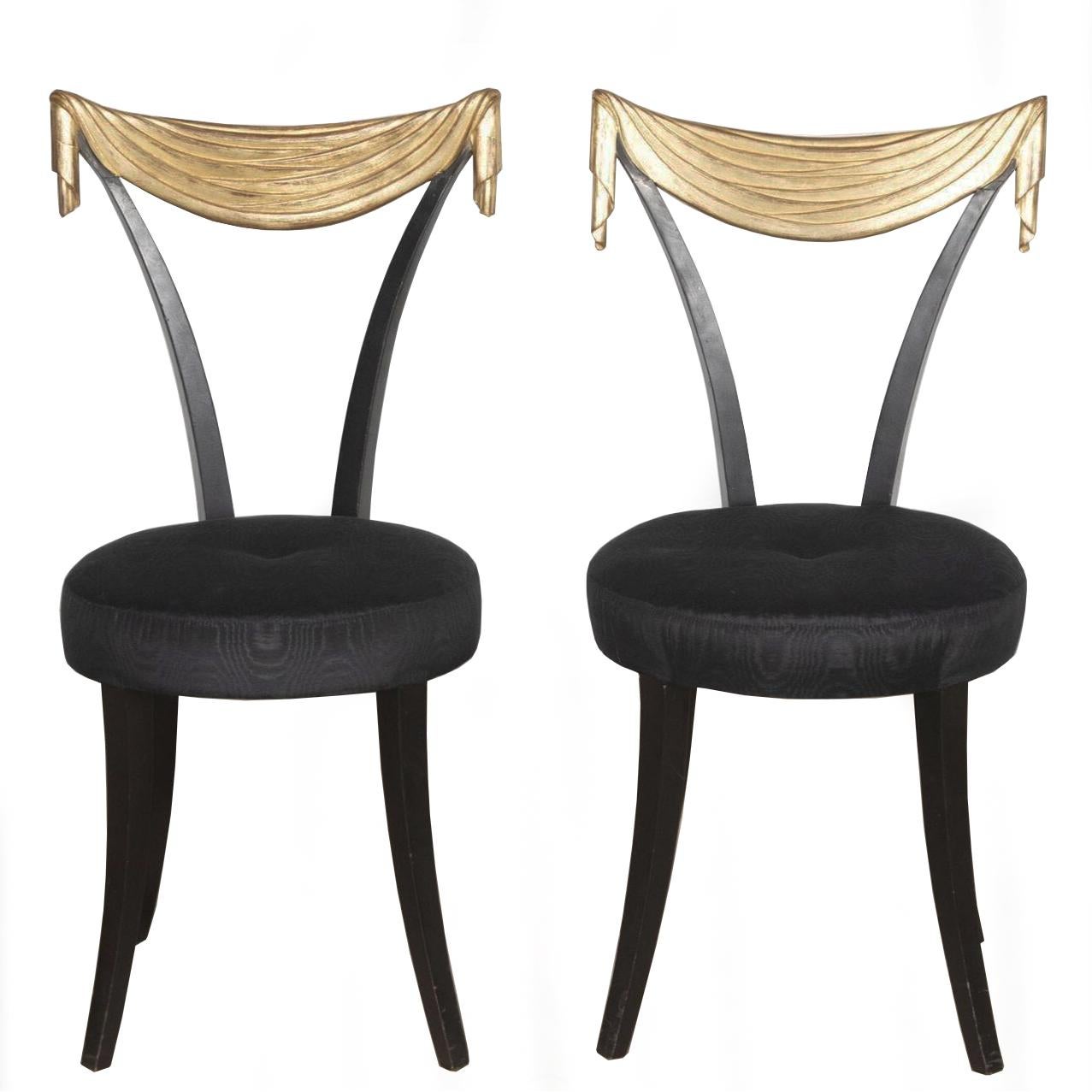 An eccentric pair of Dorothy Draper style designed ebonised side chairs with gilded drapery backs, sitting on elegantly tapered legs. 

Newly reupholstered in a sumptuous woven black silk moire.