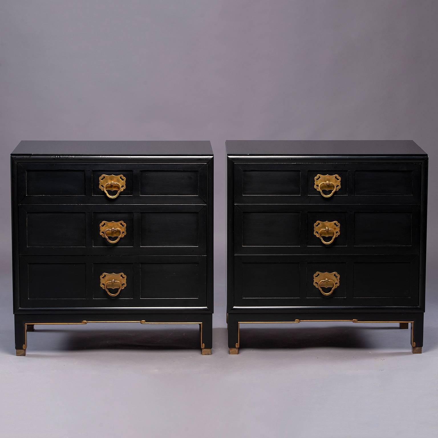 Pair of three drawer Asian style ebonized chests with black lacquer finish, gilded details, brass foot caps and brass hardware, circa early 1950s. Finish on chests has been professionally touched up and custom cut glass tops have been added for