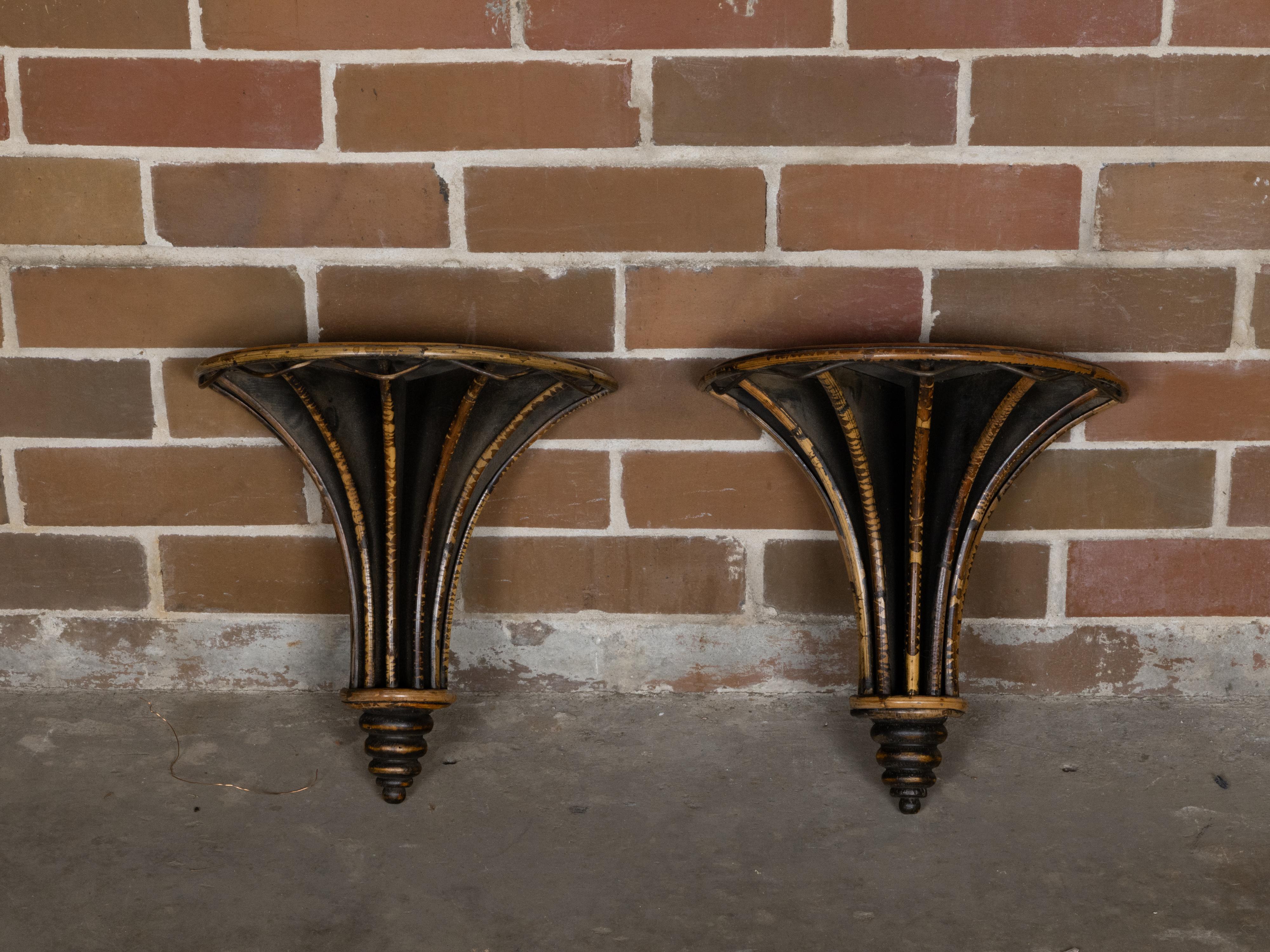 Un par de ménsulas de pared Country English ebonizadas del periodo de mediados de siglo con detalles de bambú y remates de ratán tejido. Encantándonos con su elegancia rústica, este par de ménsulas de pared Country English del periodo de mediados de