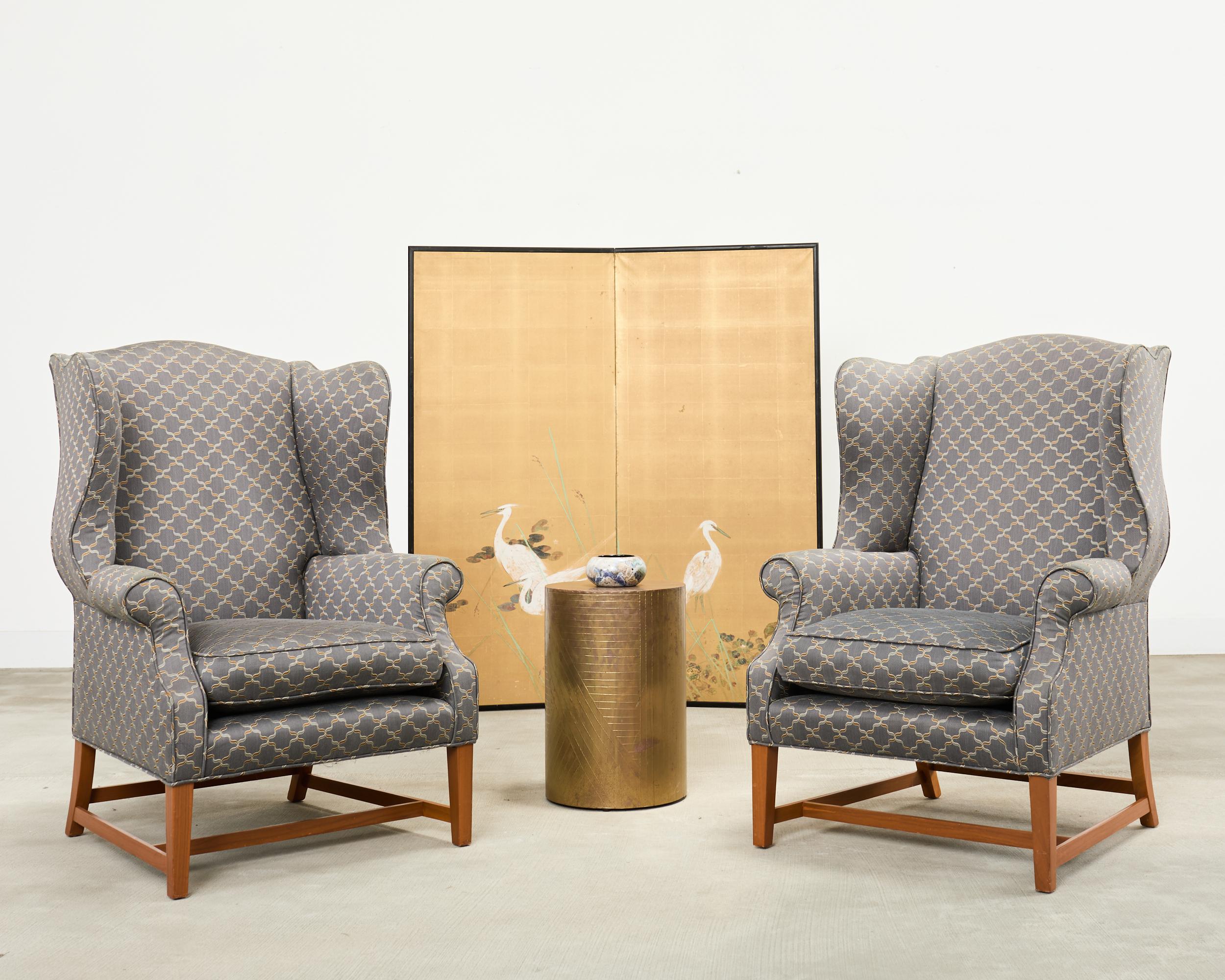 Handsome pair of bespoke midcentury wingback chairs crafted in the English Georgian taste. The chairs feature fully developed large wings on the hardwood frames. The fabric is decorated with a geometric quatrefoil silver and gold pattern over a grey