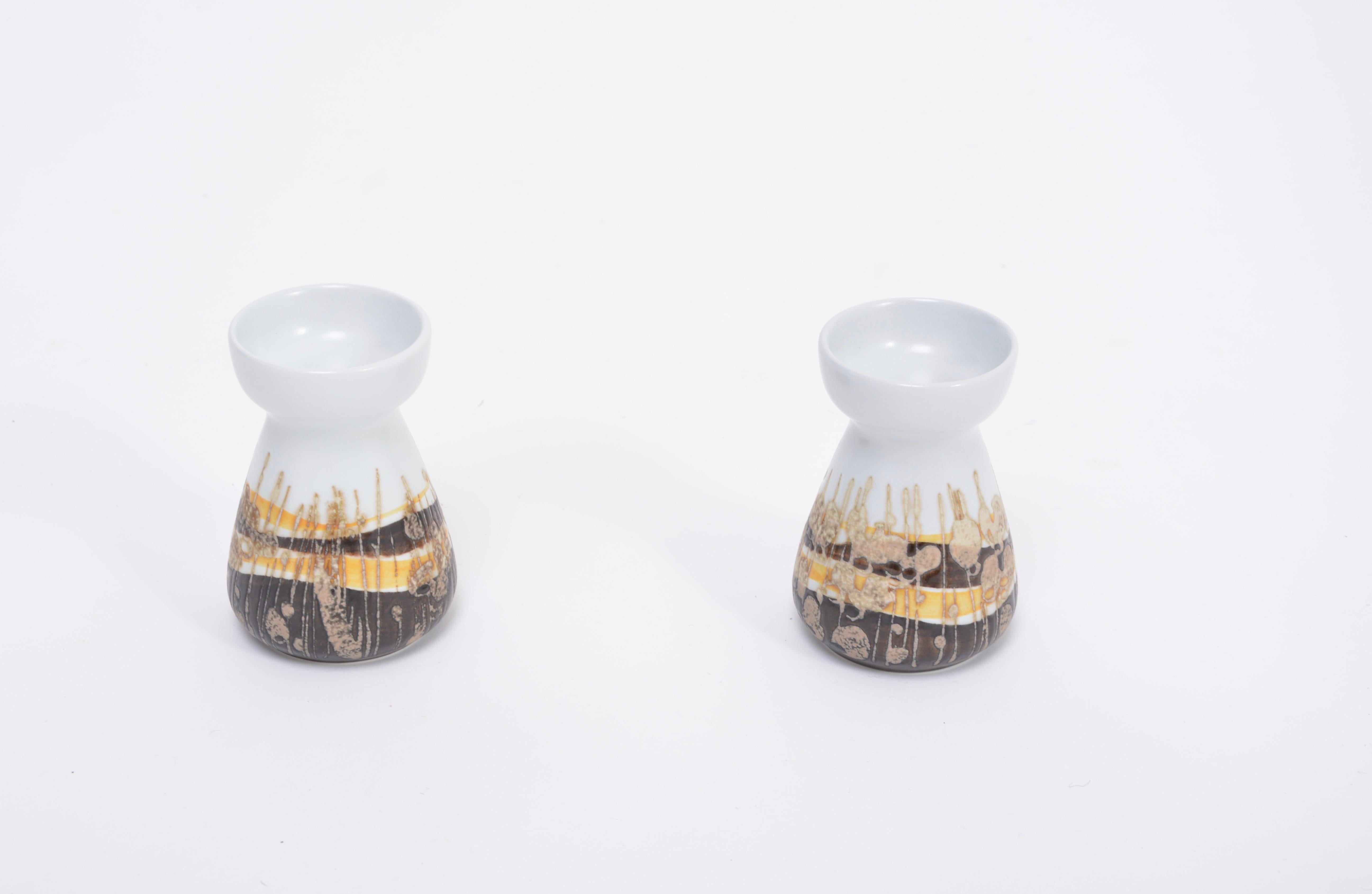 Pair of Midcentury Faience candleholders by Ivan Weiss for Royal Copenhagen 
These candle holders were designed by Nils Thorsson as part of the Baca series. Ivan Weiss designed the abstract floral pattern in colors of white, yellow and brown. They