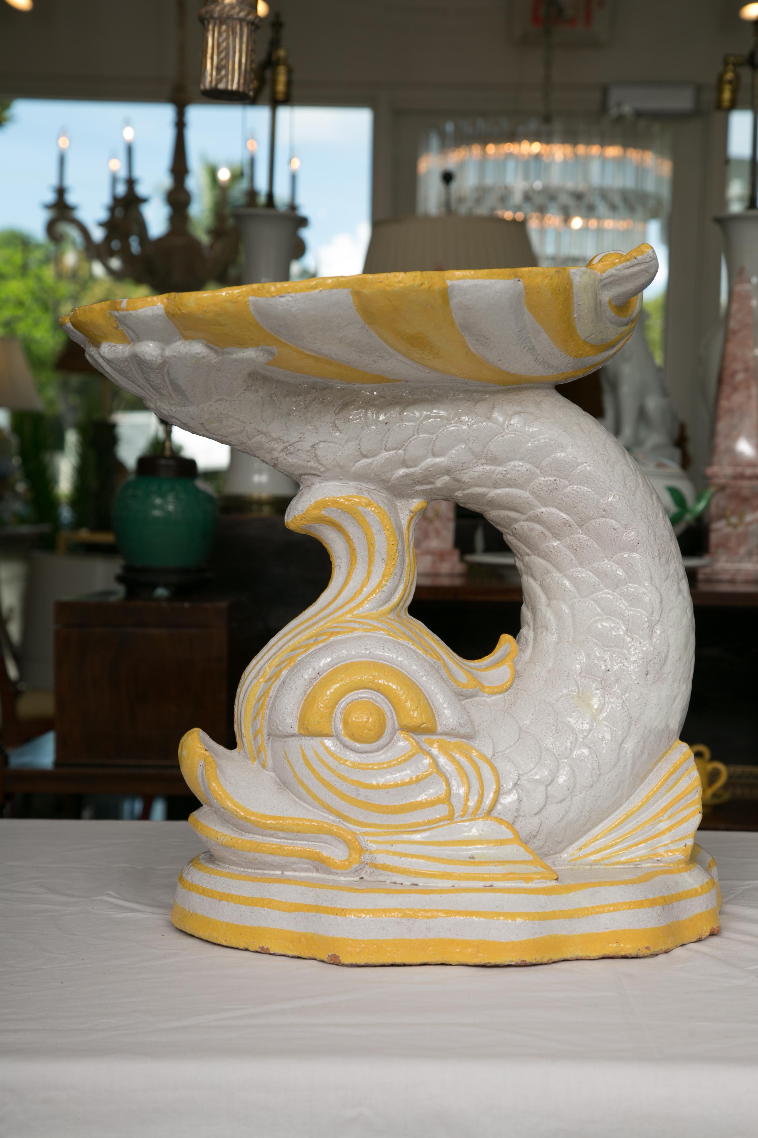 This a delightful pair of white and yellow faience glazed figures representing dolphins under a large scalloped shell, mid-20th century.