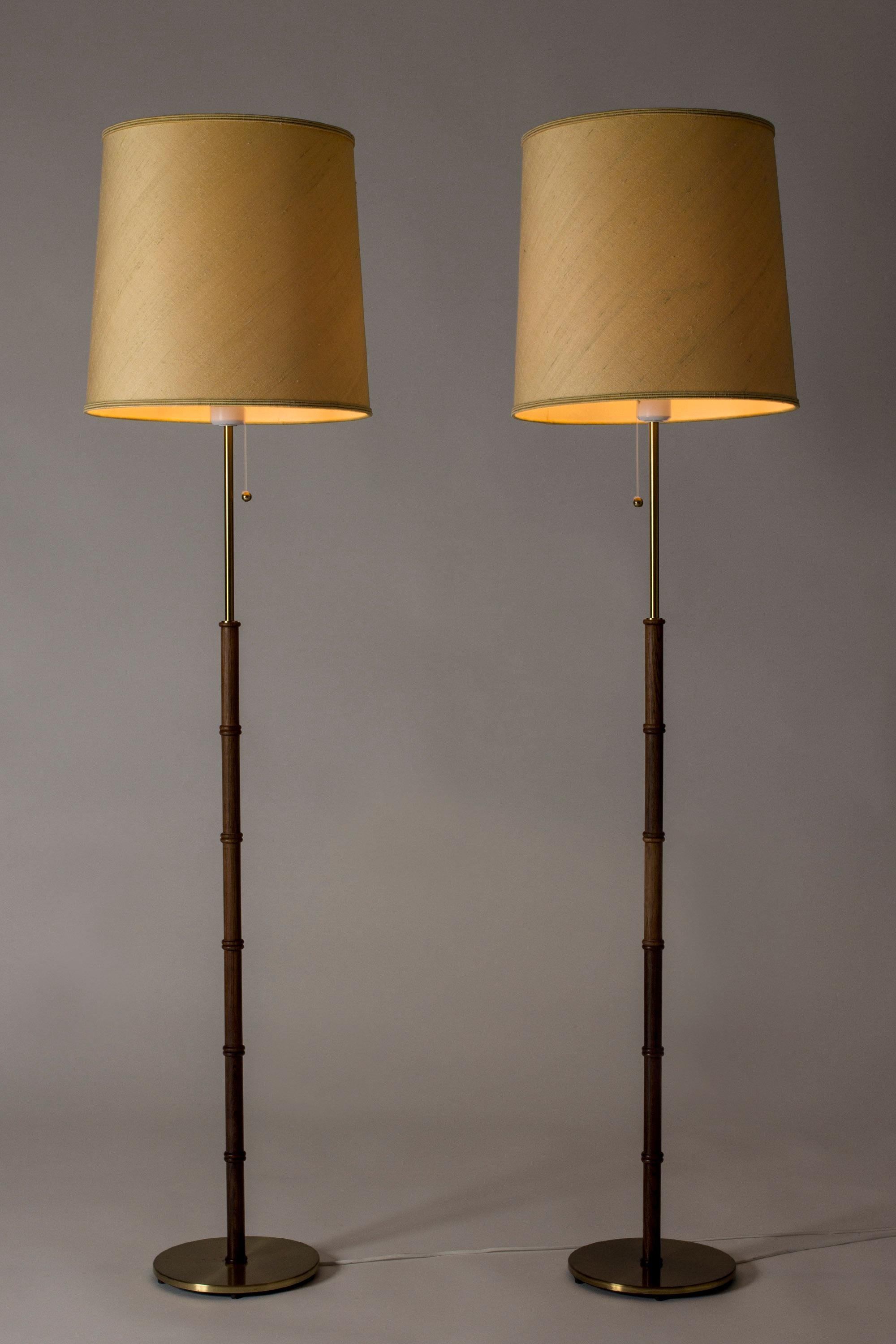 Pair of cool floor lamps from Falkenbergs Belysning, made from brass with rosewood stems. Wood nicely carved into a bamboo-stem form, great woodgrain. Original oversized shades.