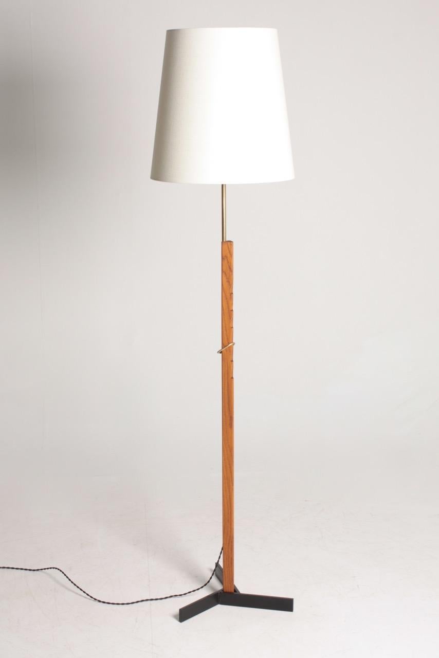 Pair of height adjustable floor lamps in oak and brass on a black metal base, designed and made by Holm Sorensen, Denmark in the 1950s. Great original condition.