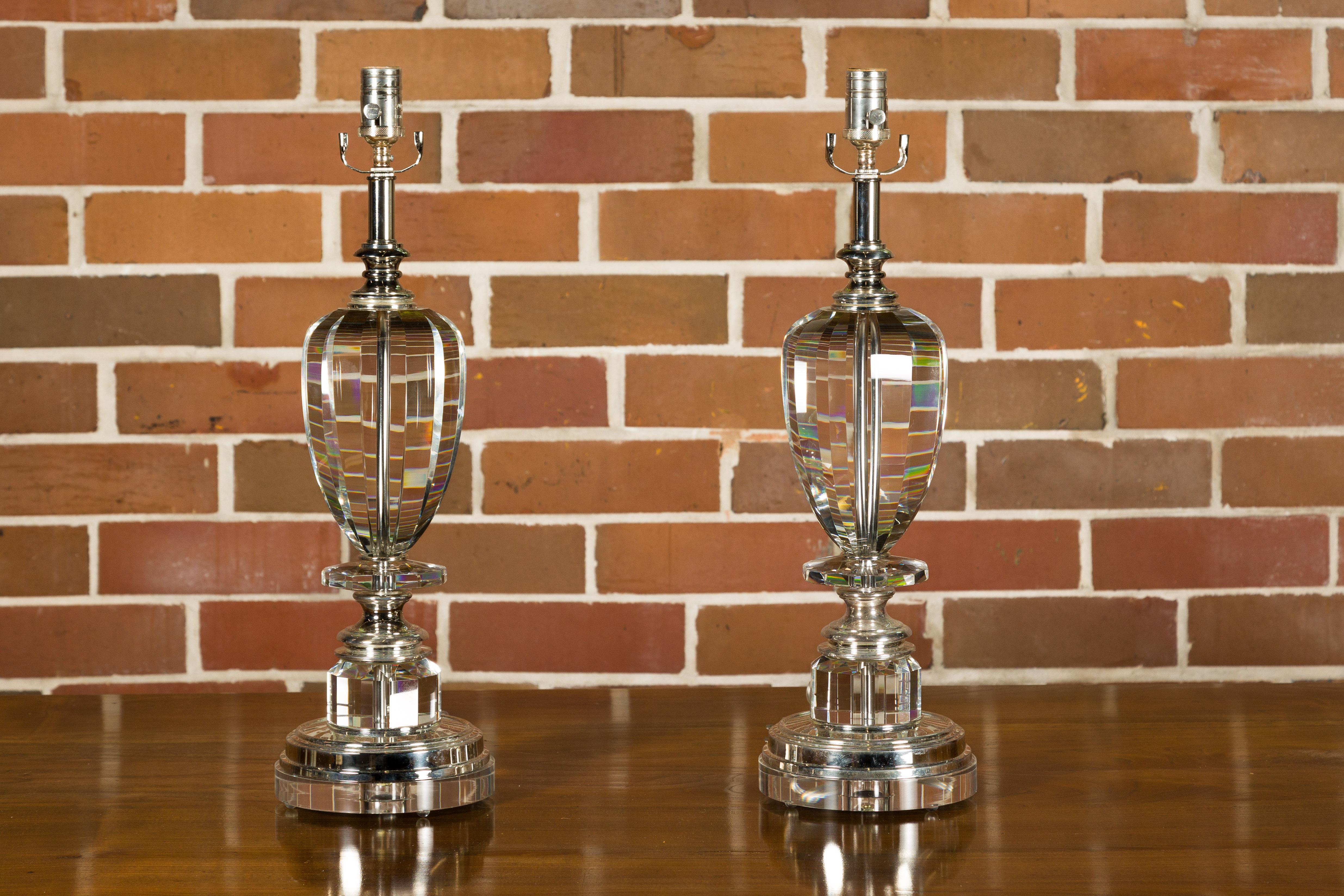 A pair of French crystal single-light table lamps from the mid 20th century on circular lucite bases, wired for the USA. This exquisite pair of French crystal table lamps from the mid-20th century is a testament to timeless elegance and