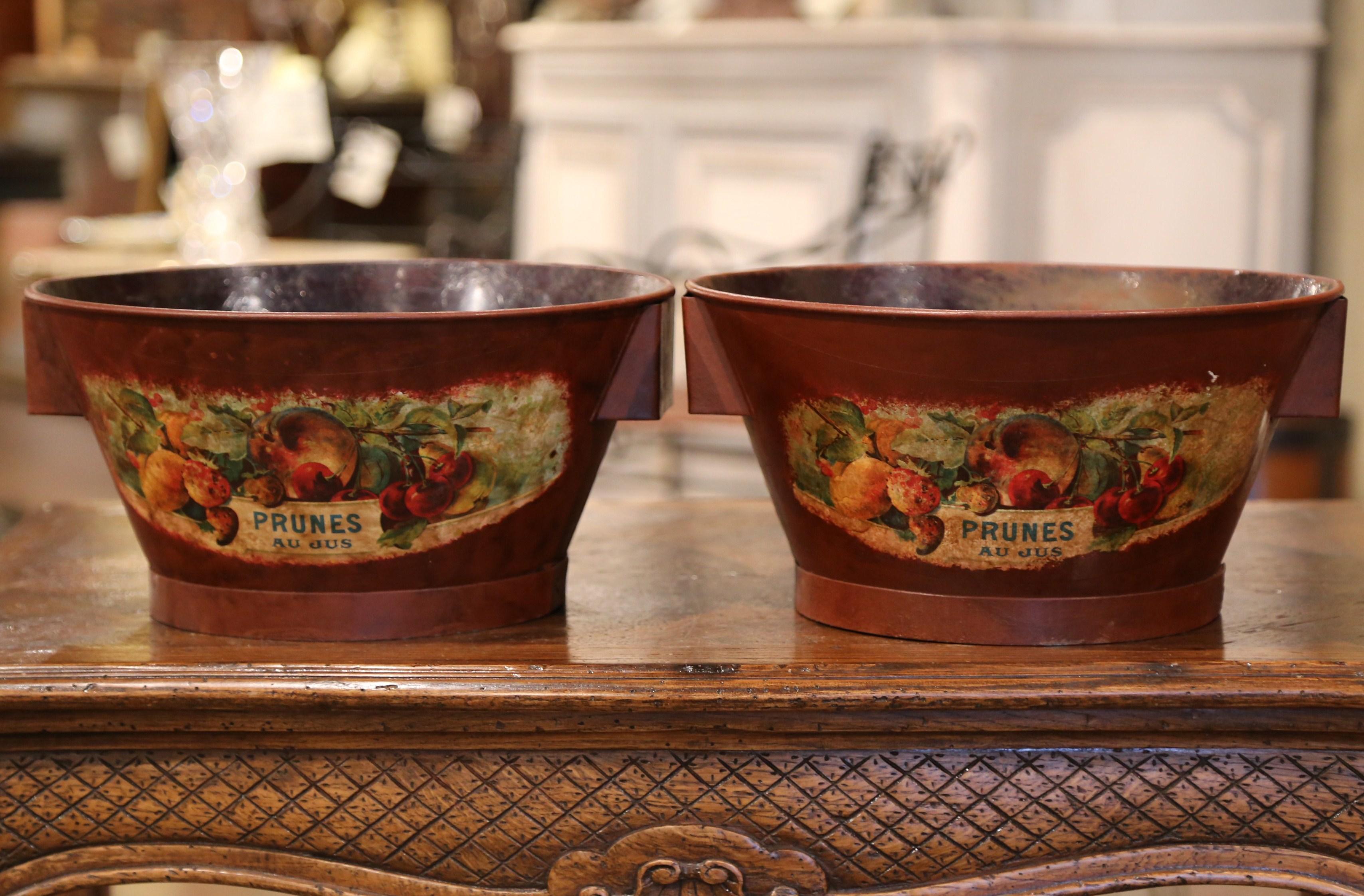 Accessorize a kitchen with this pair of decorative baskets. Crafted in France circa 1970, each metal bowl is round in shape and features hand painted fruit decor with 