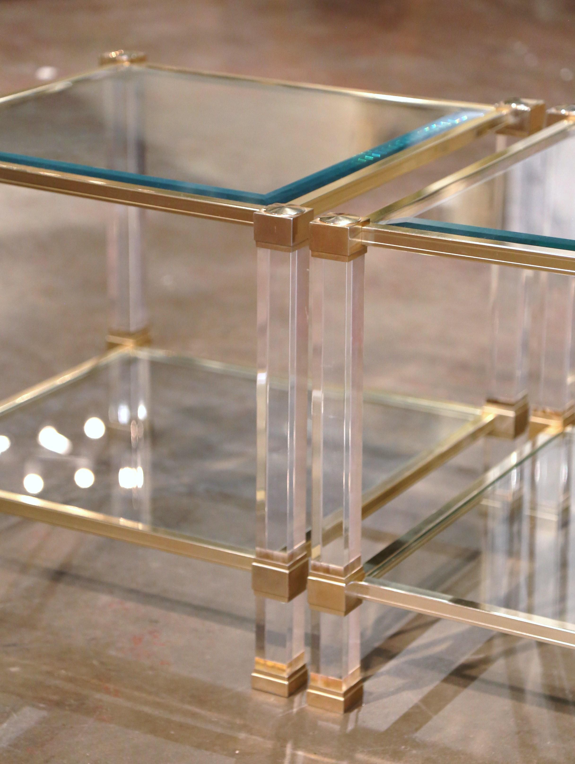 Decorate a den or living room with this elegant pair of vintage side tables. Crafted in France circa 1970 and attributed to Pierre Vandel, each table stands on four square clear plexiglass legs over a gilt metal frame. The top and the bottom shelf