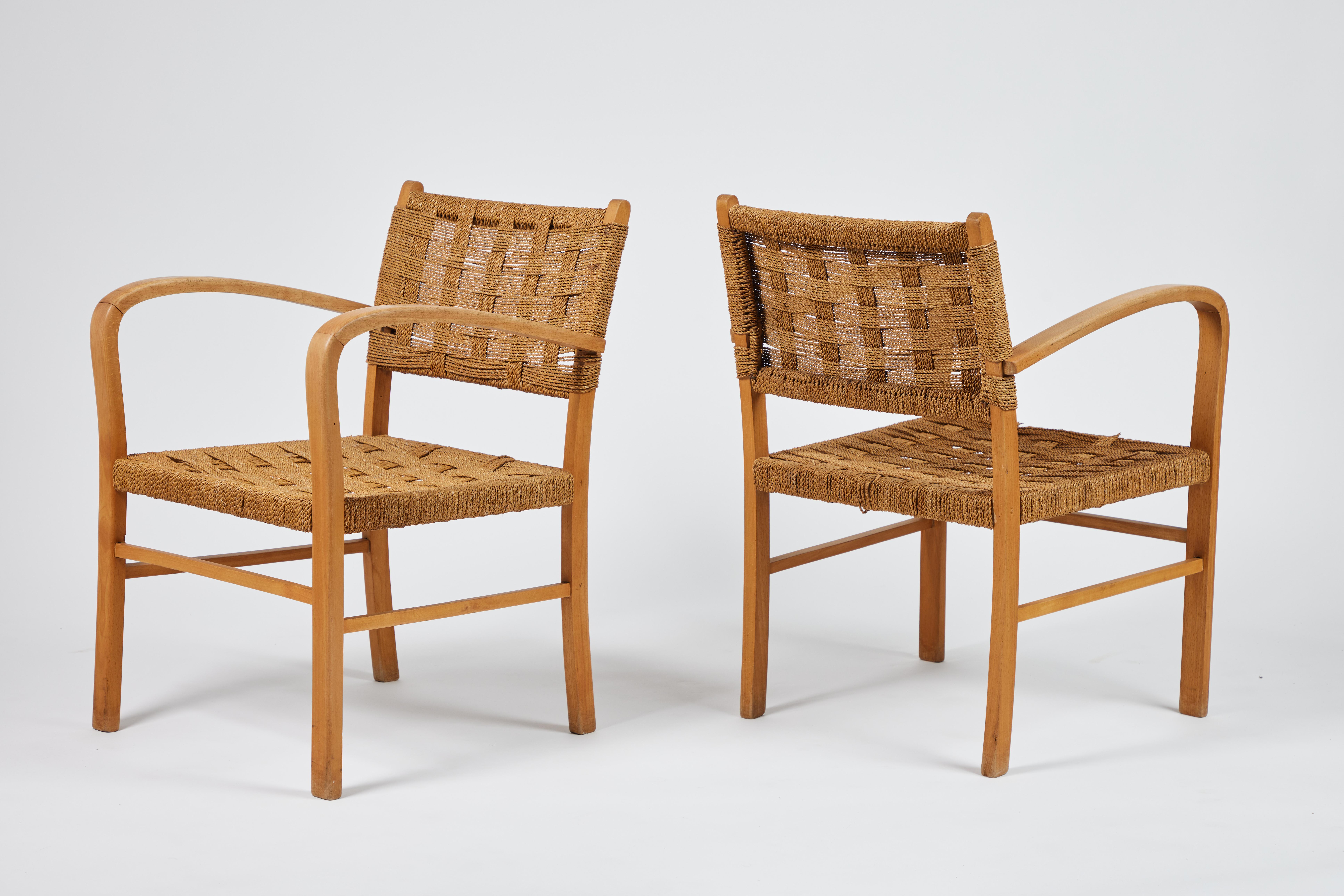Pair of mid-century French oak arm chairs with curved, sculptural arms. Woven seat and back supports are comprised of groups of 8 thin ropes form each 