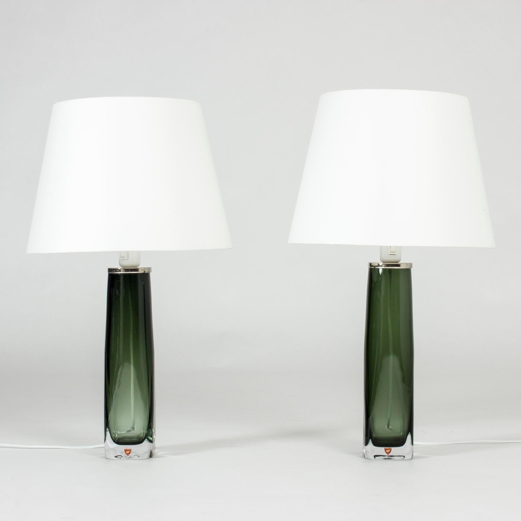 Pair of elegant translucent green glass table lamps by Carl Fagerlund for Orrefors. Heavy glass bases with a slender shape and white metal detail at the top. Beautiful in a window.