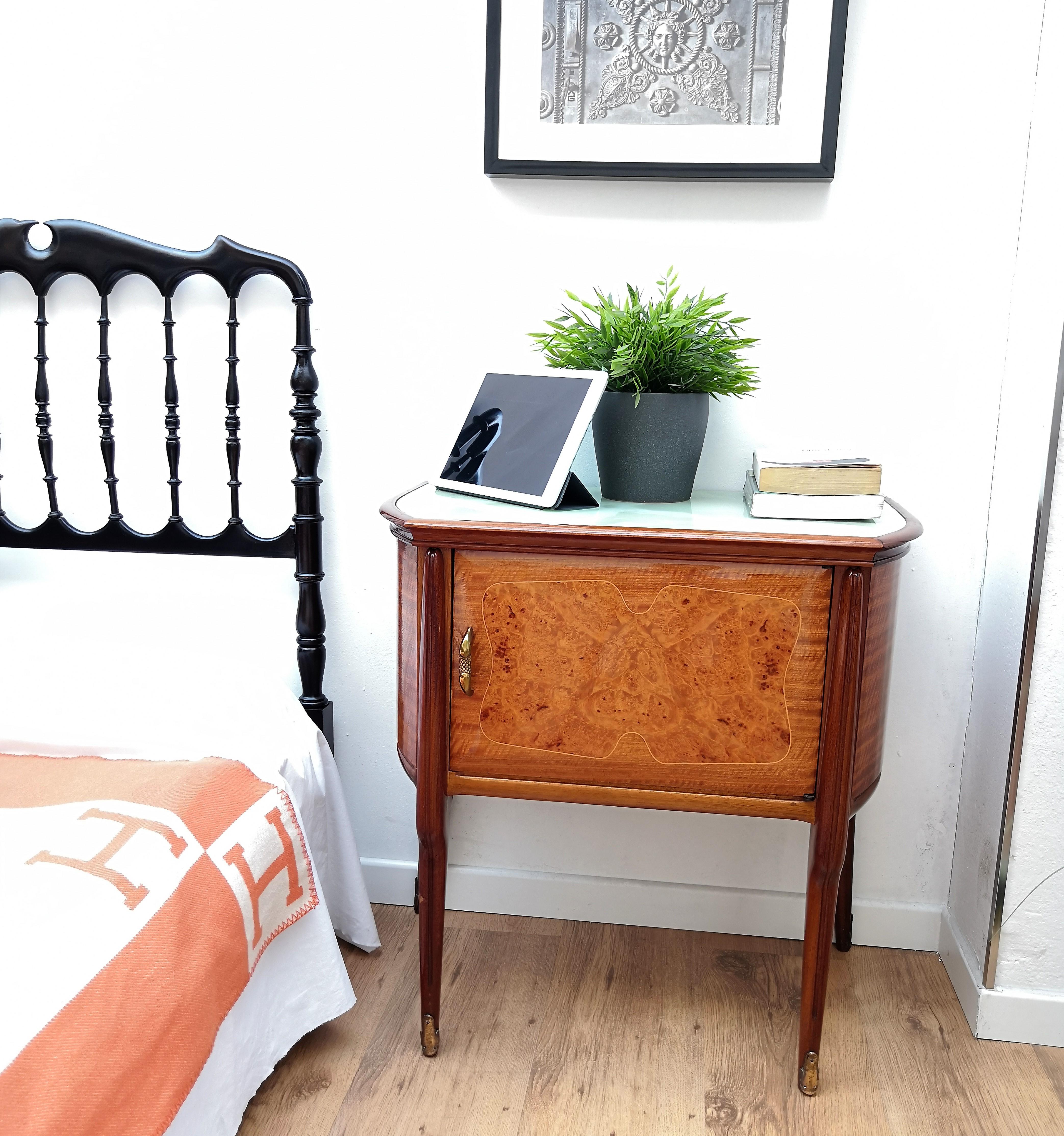 Very elegant and refined Italian 1950s pair of bedside tables, nightstands in solid walnut with great burl veneer wood and gilt inlay frontal door decors with a top onix decorated glass inlay and brass details such as the 2 handles and the 4 foot