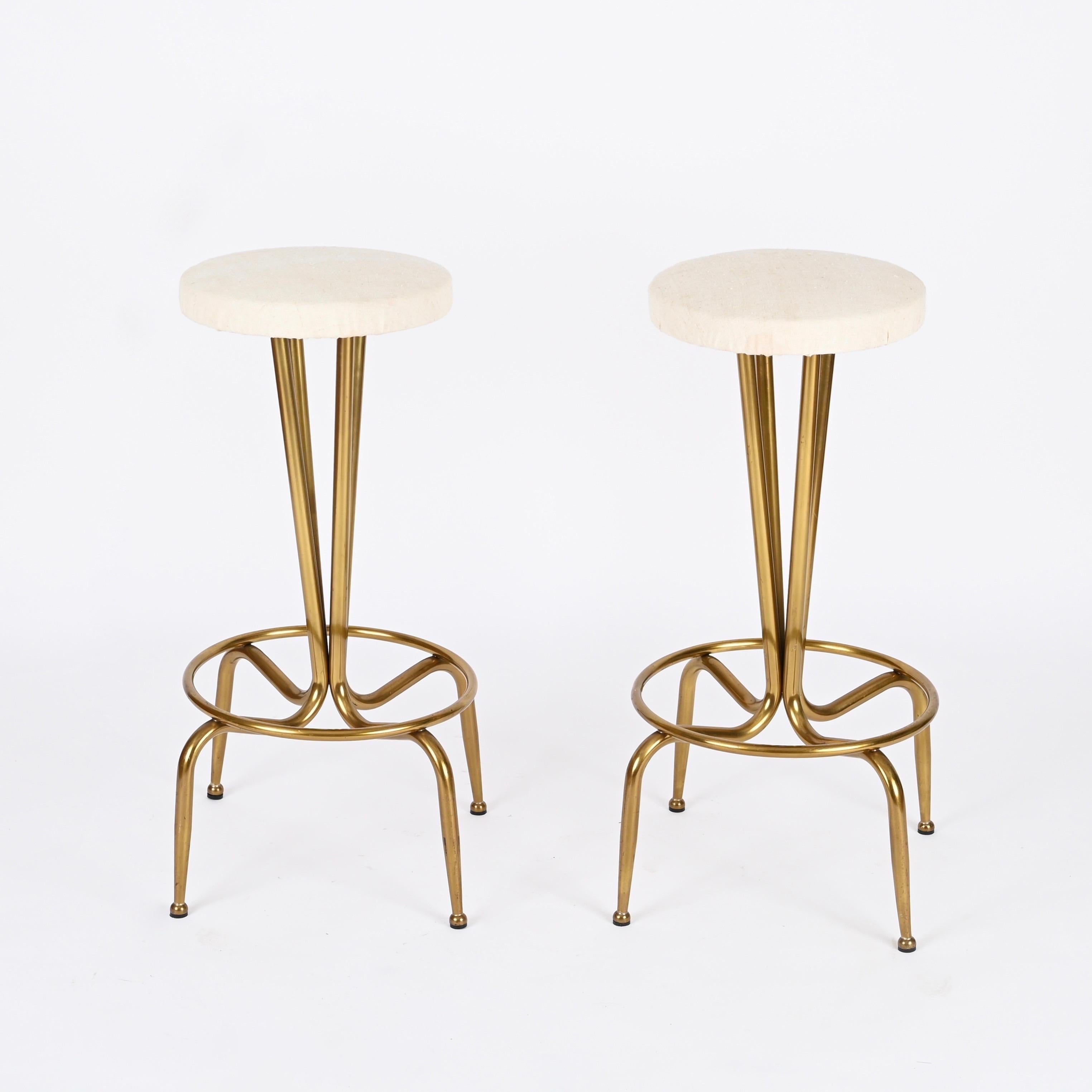 Merveilleuse paire de tabourets de bar Mid-Century Modern en laiton courbé doré avec une assise en tissu de coton écru. Cette magnifique paire de tabourets a été conçue en Italie dans les années 1950 et est attribuée à la maîtrise de Gio Ponti.

Les